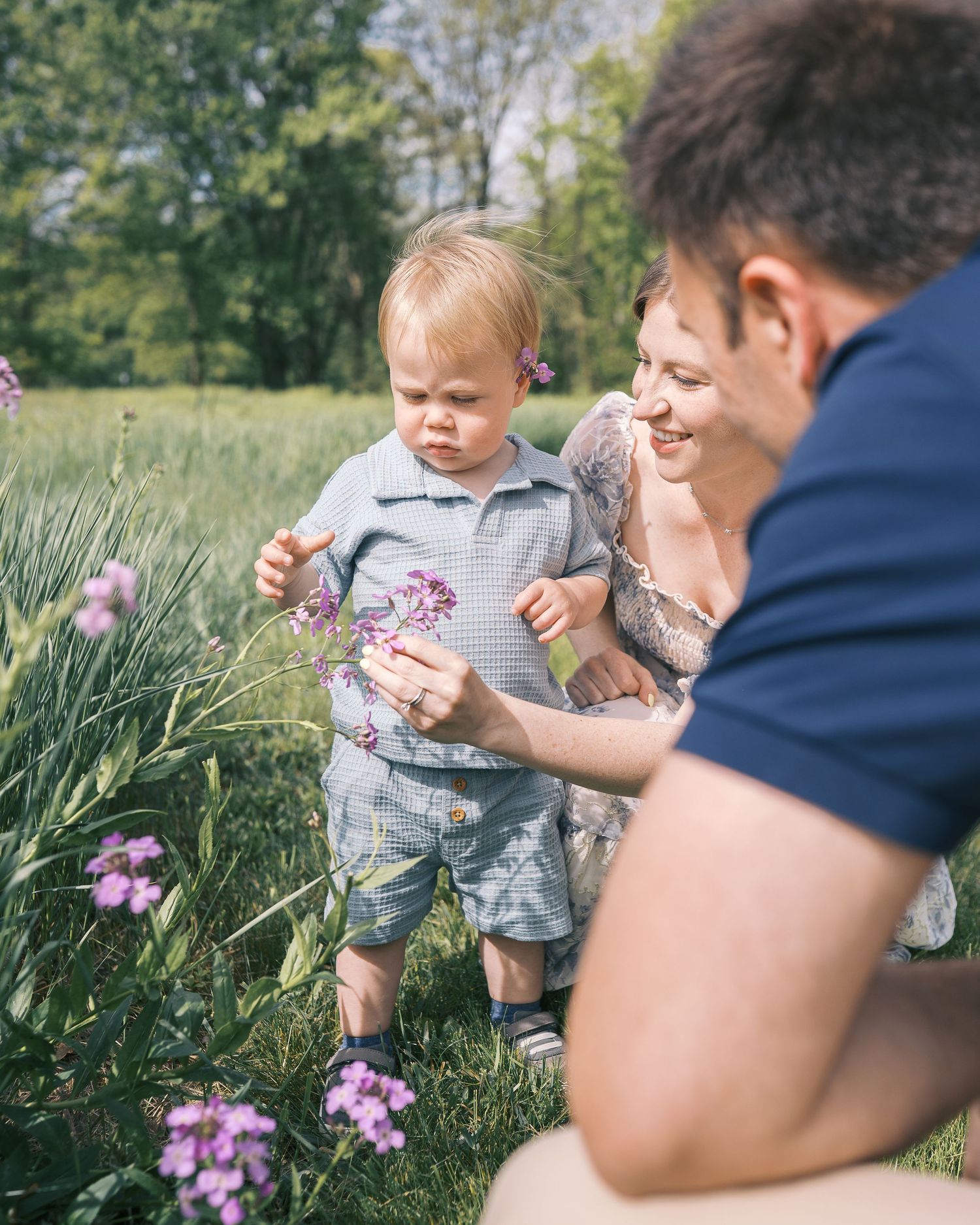 Family spending time together in a field with purple wildflowers on a sunny day.