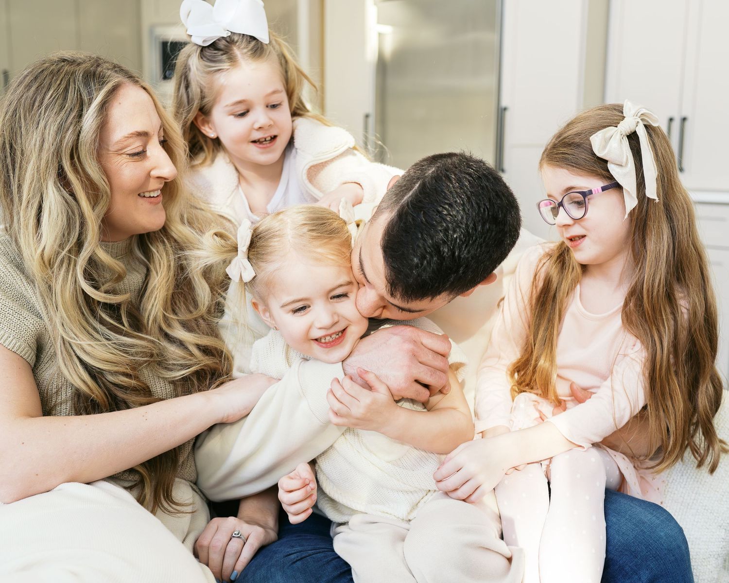 Candid family photography showing affectionate interactions on a white sofa.