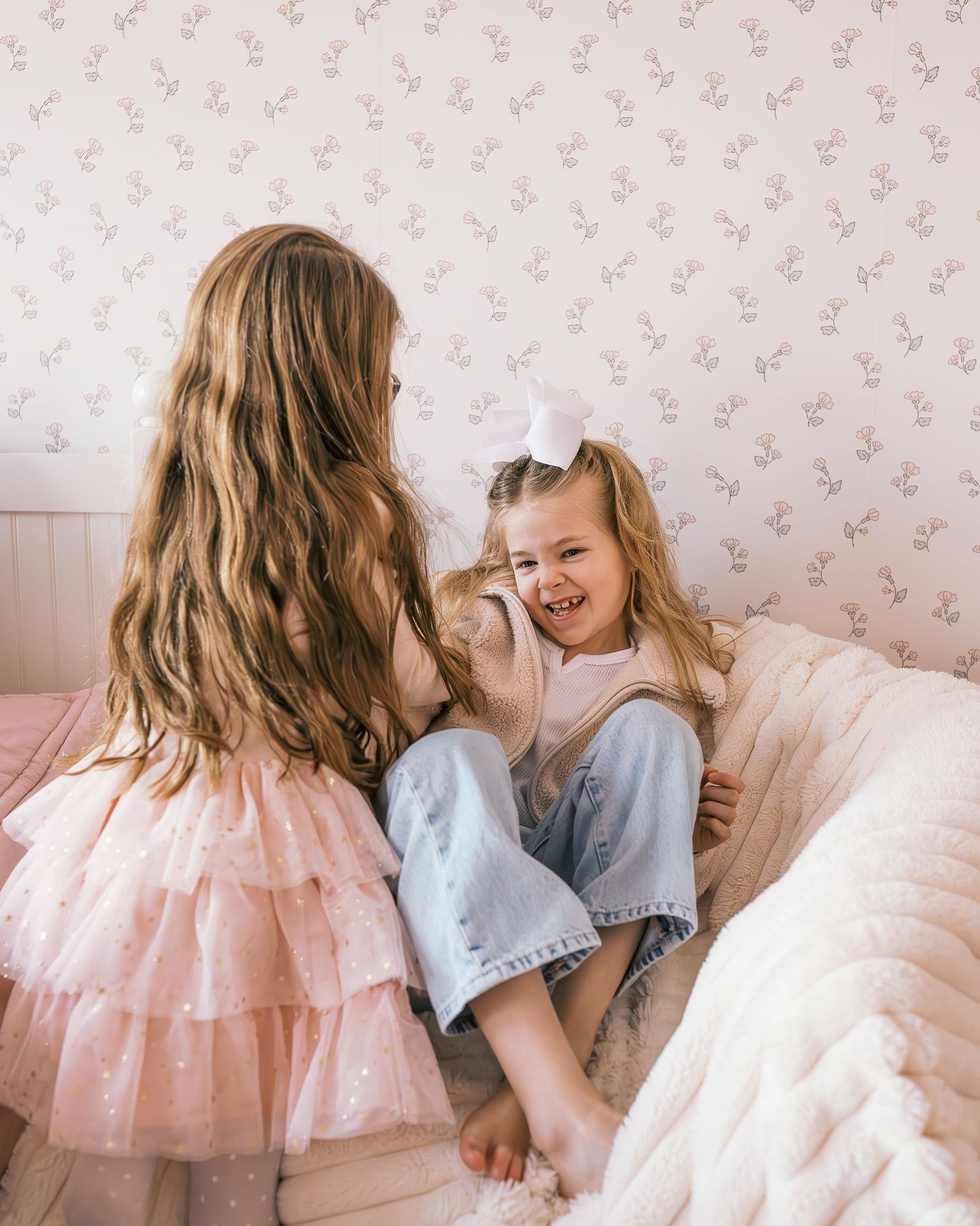 Sweet interactions on bed with floral wallpaper backdrop in pastel tones.