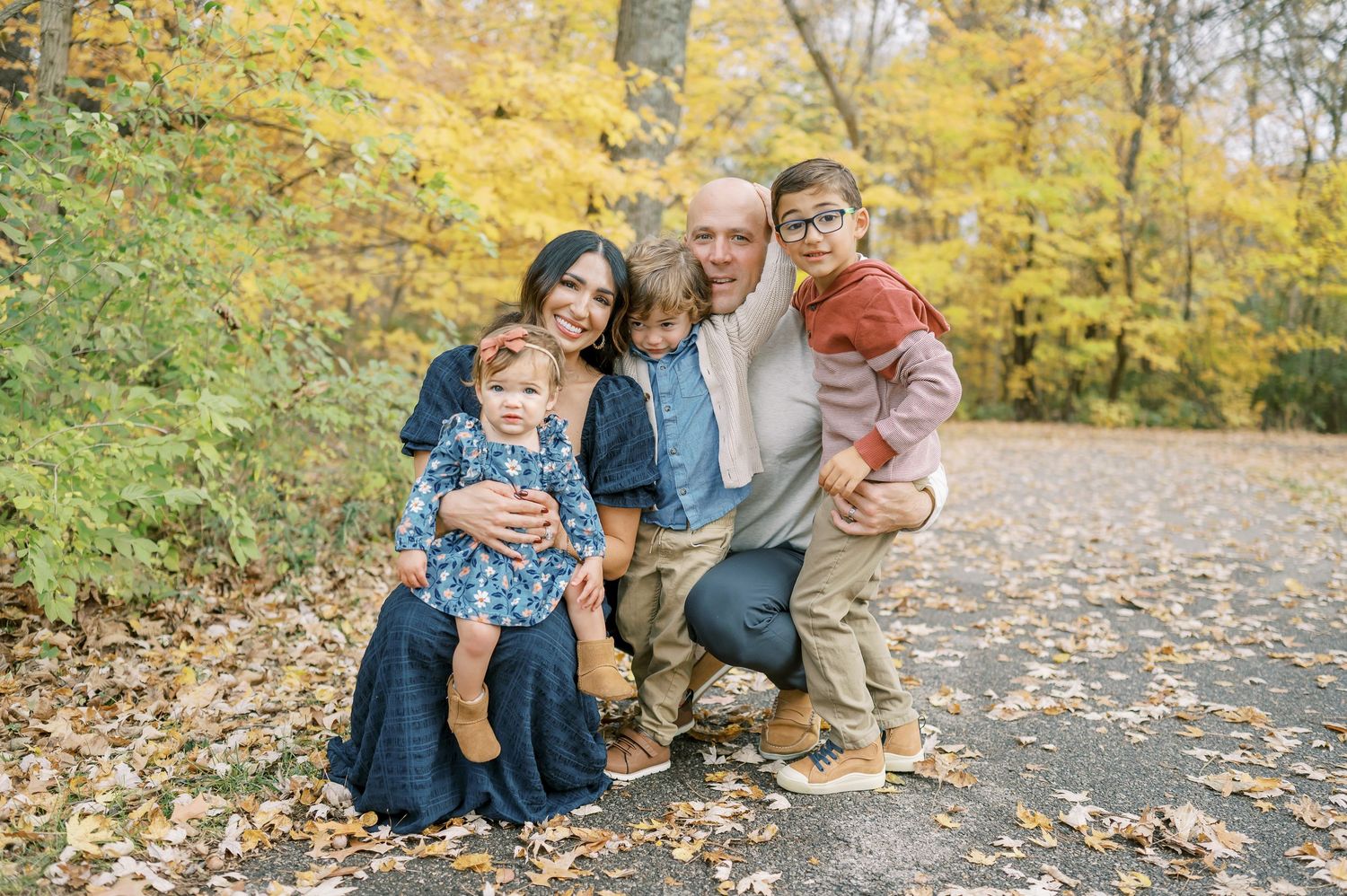 Candid family moments captured during autumn photoshoot with yellow leaves in background.