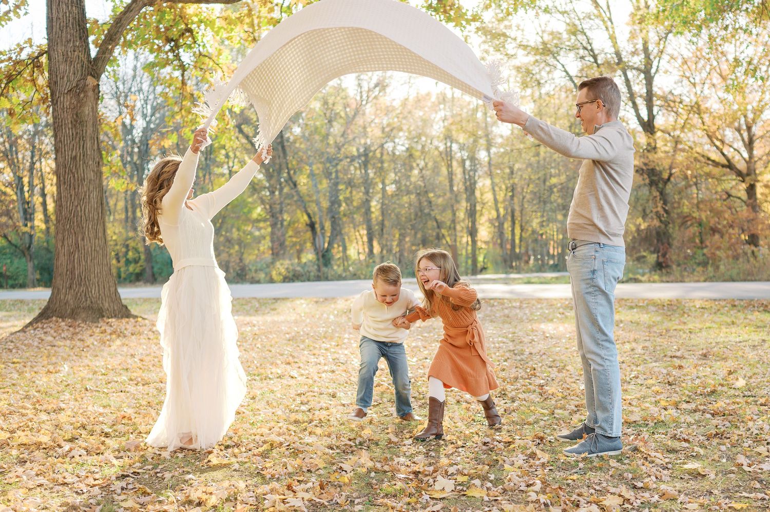 Wide panoramic view of family photo session in autumn park with golden light.