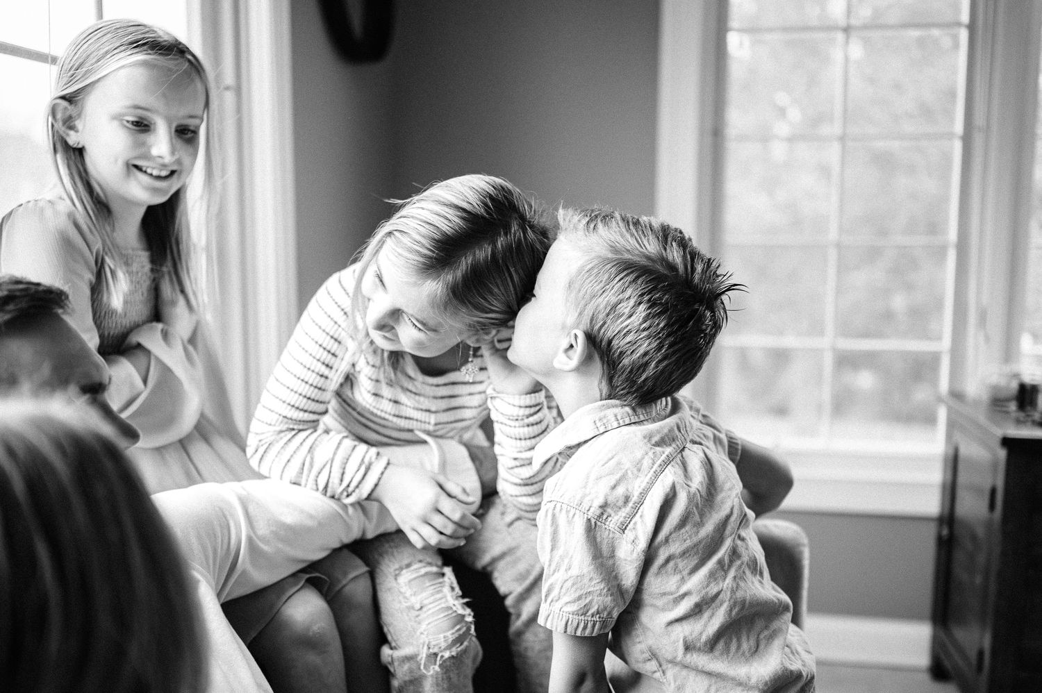 Candid black and white photo of family sharing playful moment indoors.