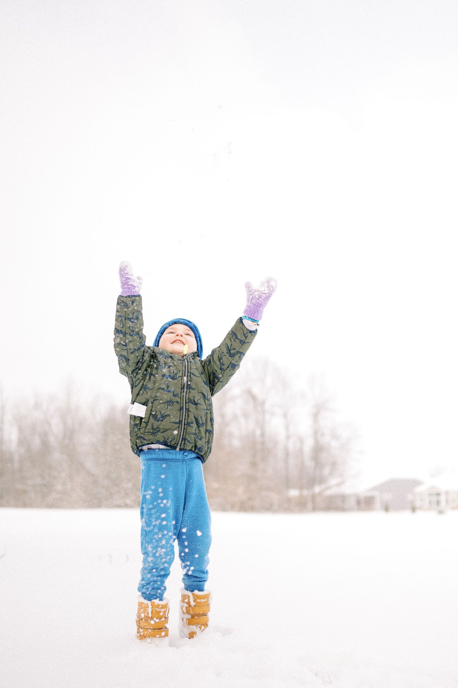 A figure jumps joyfully in the deep winter snow with arms raised.