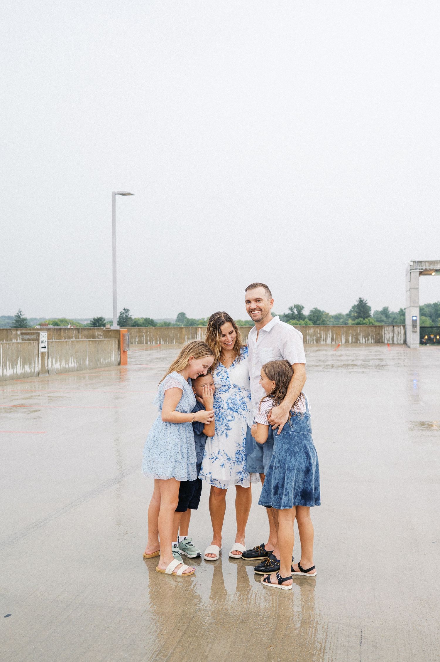 A casual group photo session takes place on a beachside boardwalk with cloudy skies.
