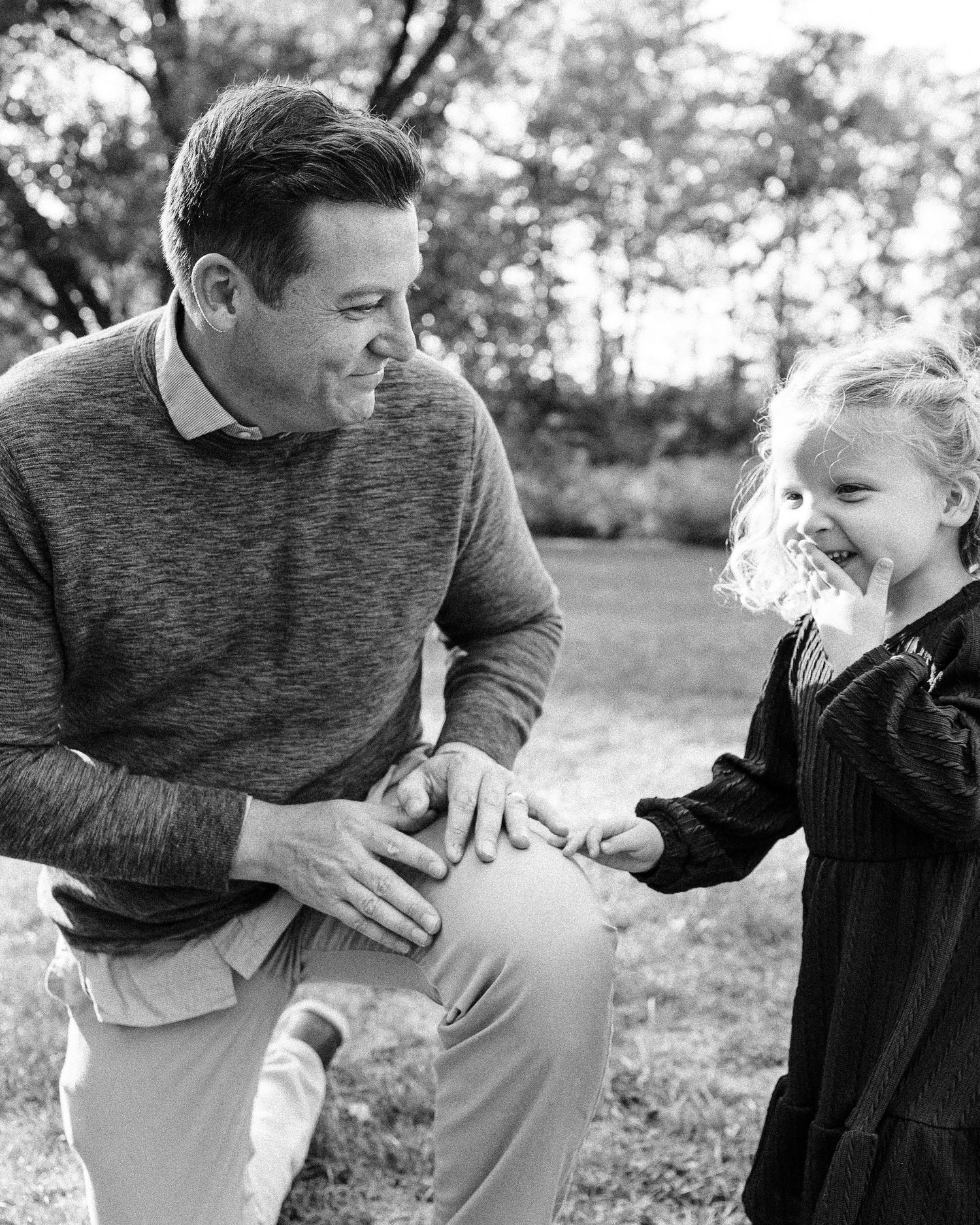 A playful sequence of black and white photos showing joyful interaction outdoors in a park setting.
