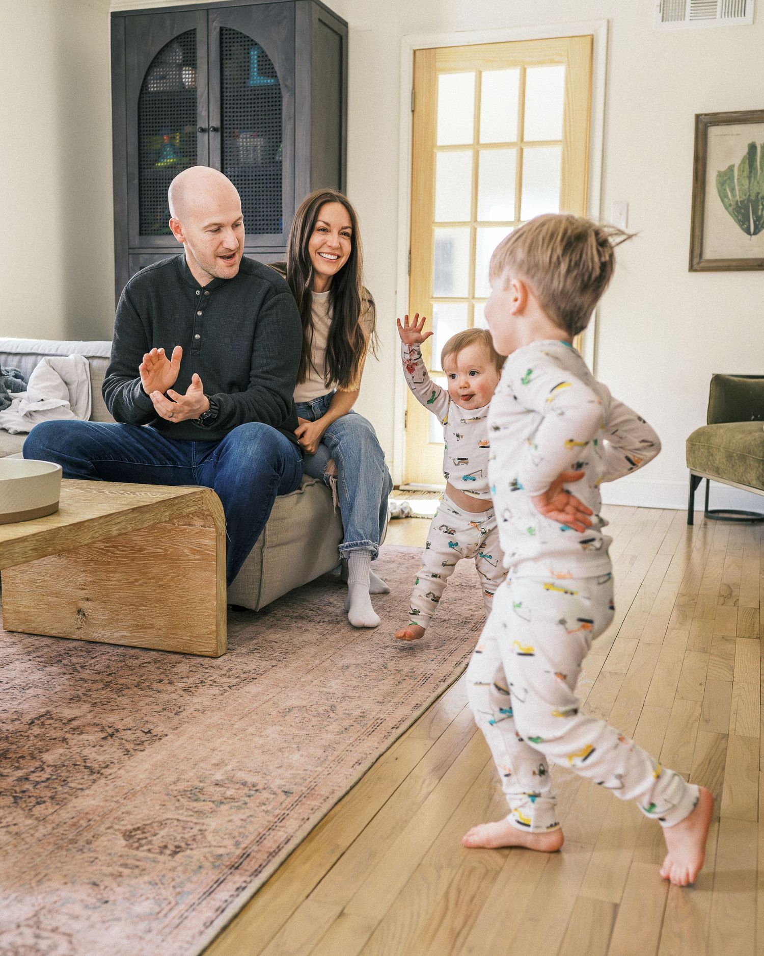 Family playing together in modern living room with hardwood floors and decorative cabinet.