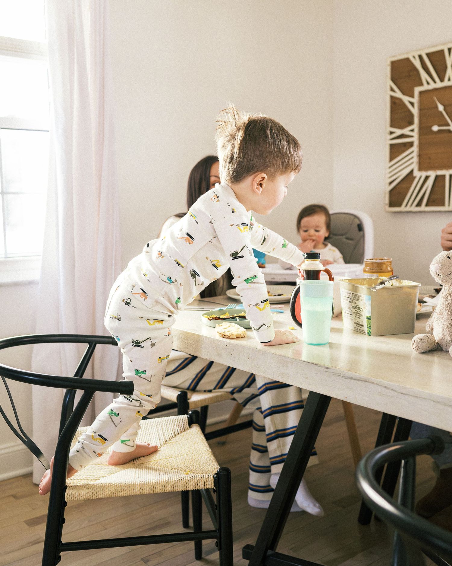 Multiple views of a modern dining area with kids sitting at a white table with black chairs.