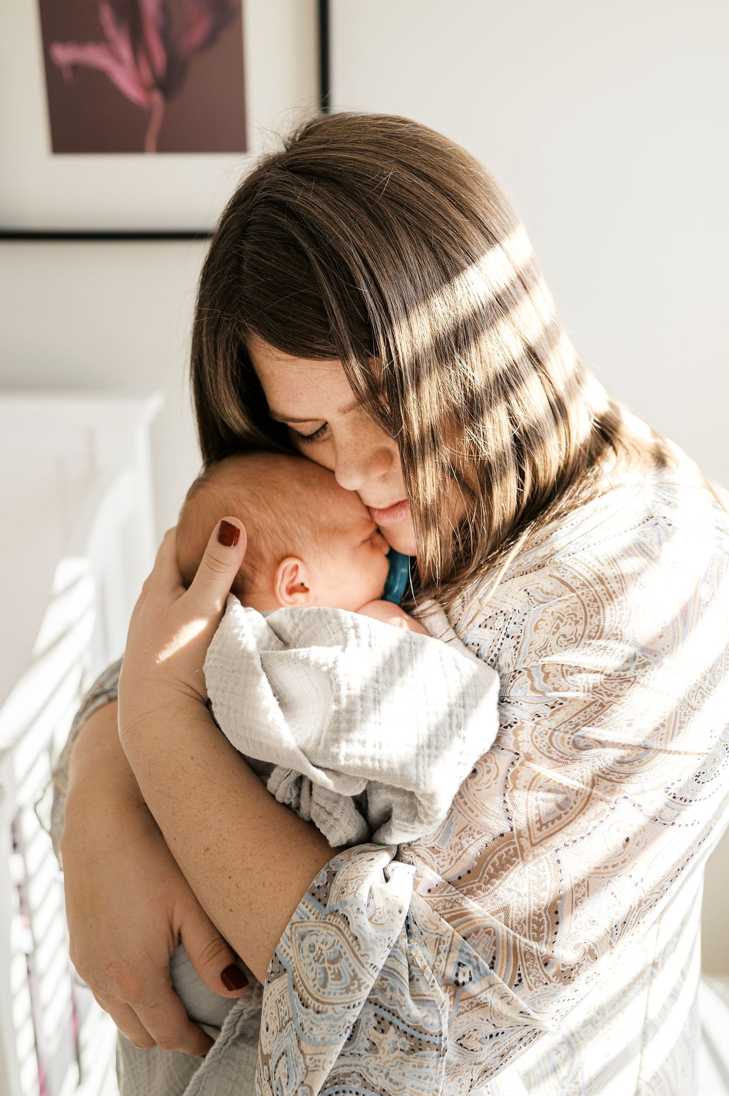 Intimate lifestyle portraits showing parent bonding with newborn in window light.