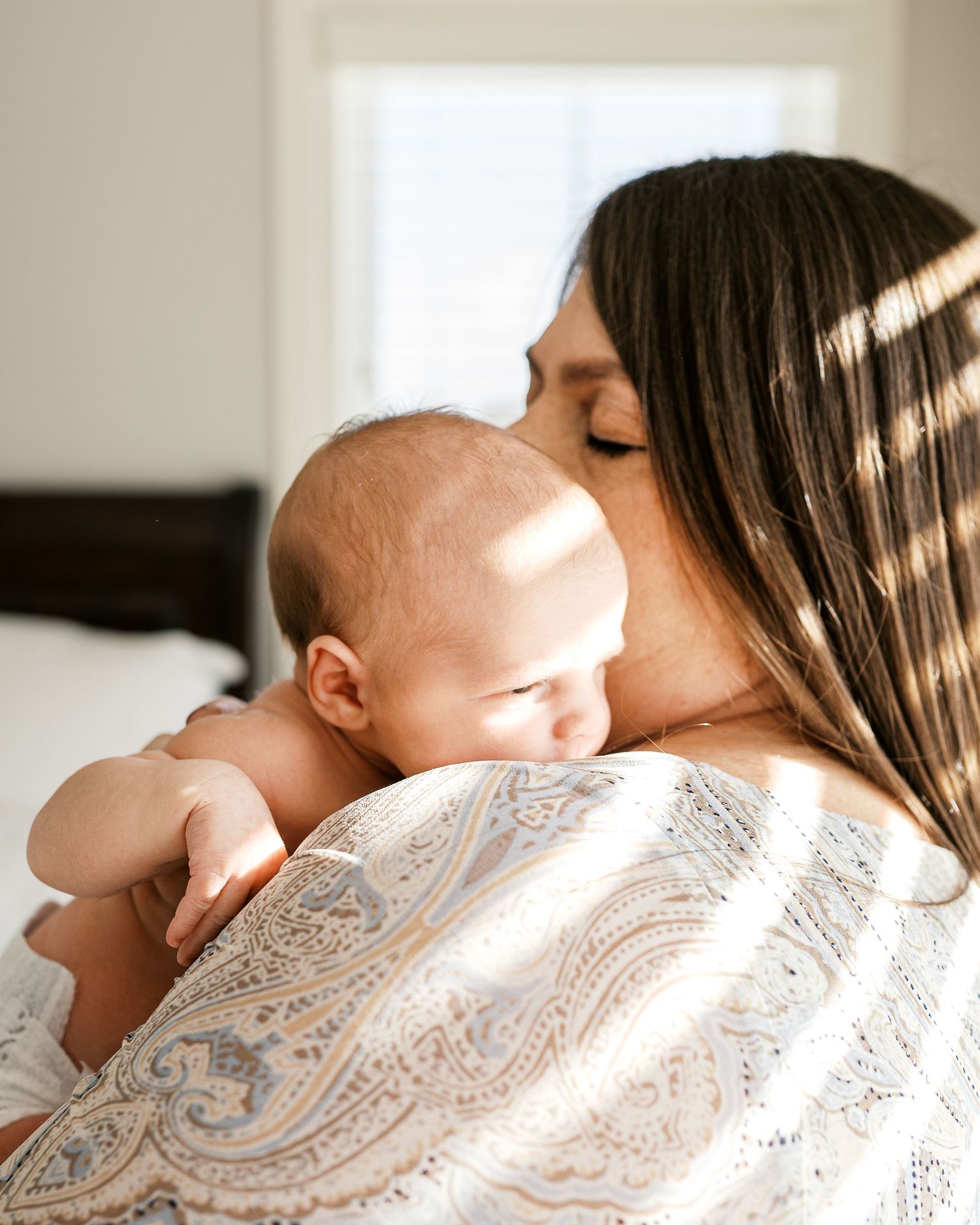 Intimate portrait of a tender moment between parent and newborn in soft natural lighting.