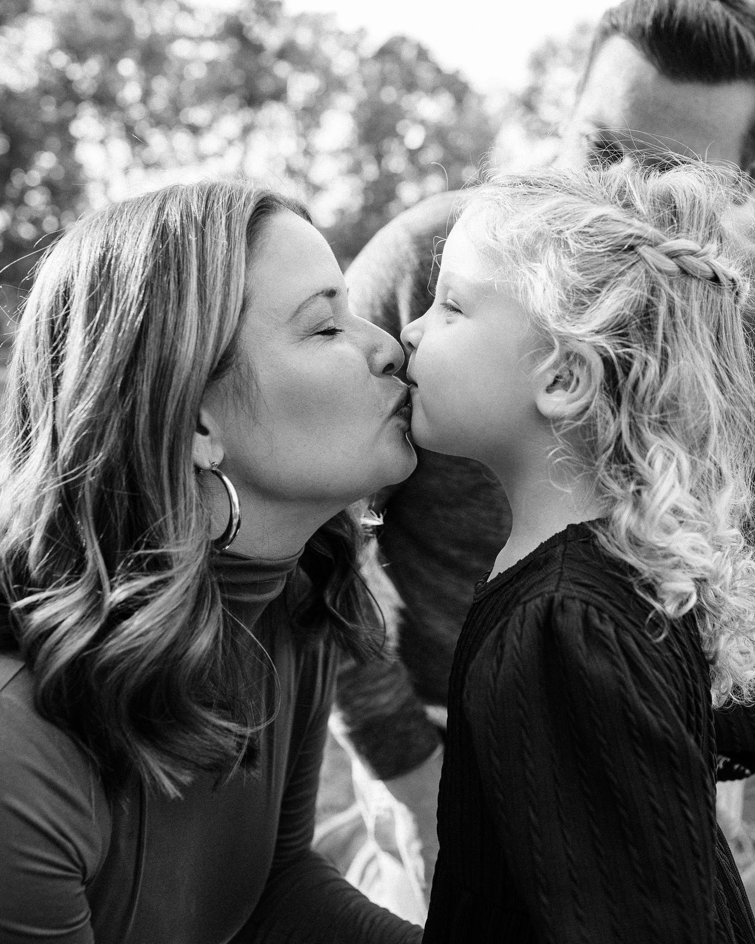 Black and white photo sequence showing a tender kiss between two people in an outdoor setting.