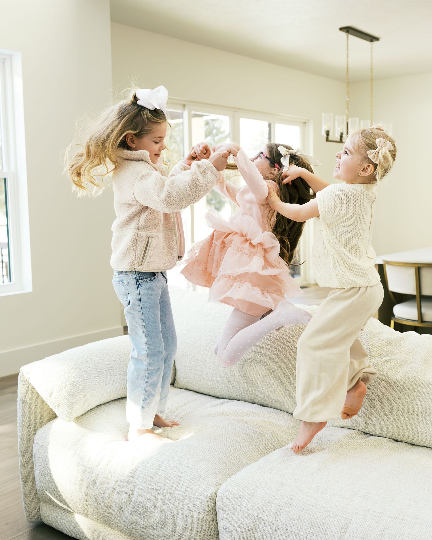 Natural light photography of a family's energetic moments on their living room sofa.