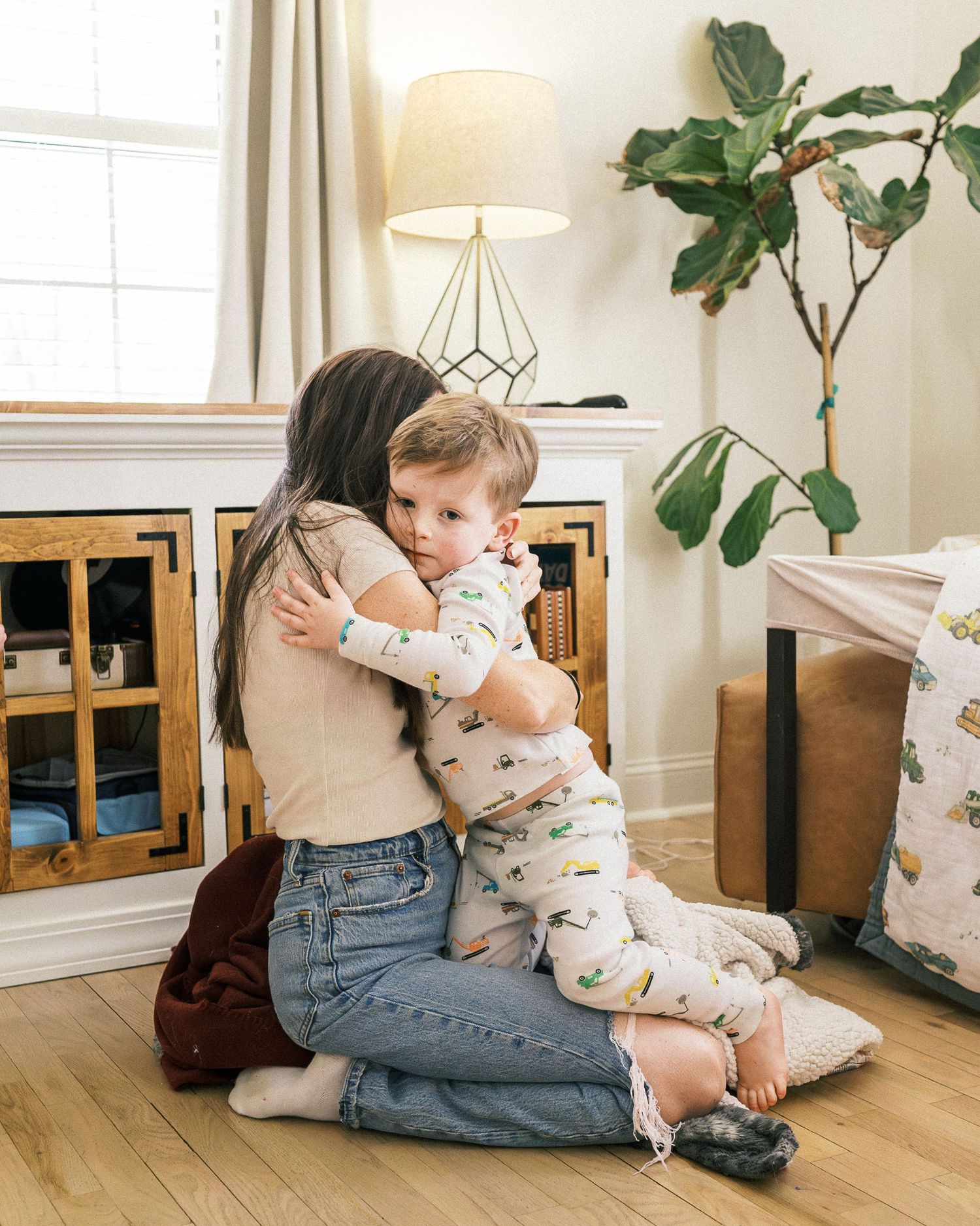 Tender moment shared on hardwood floor with fiddle leaf fig plant and modern decor.