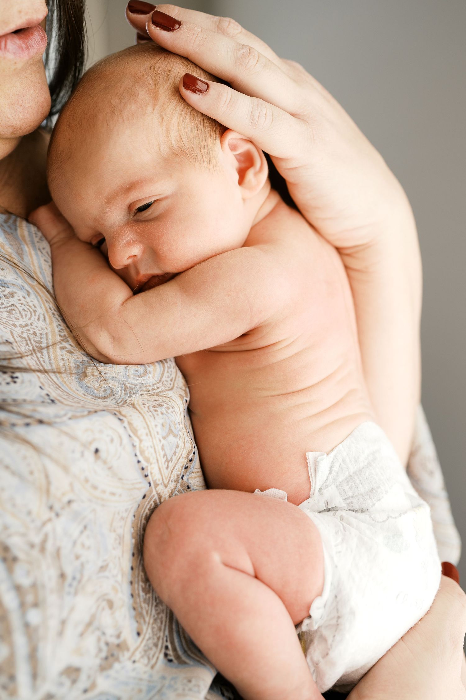 Peaceful newborn resting against parent wearing a delicate lace top.