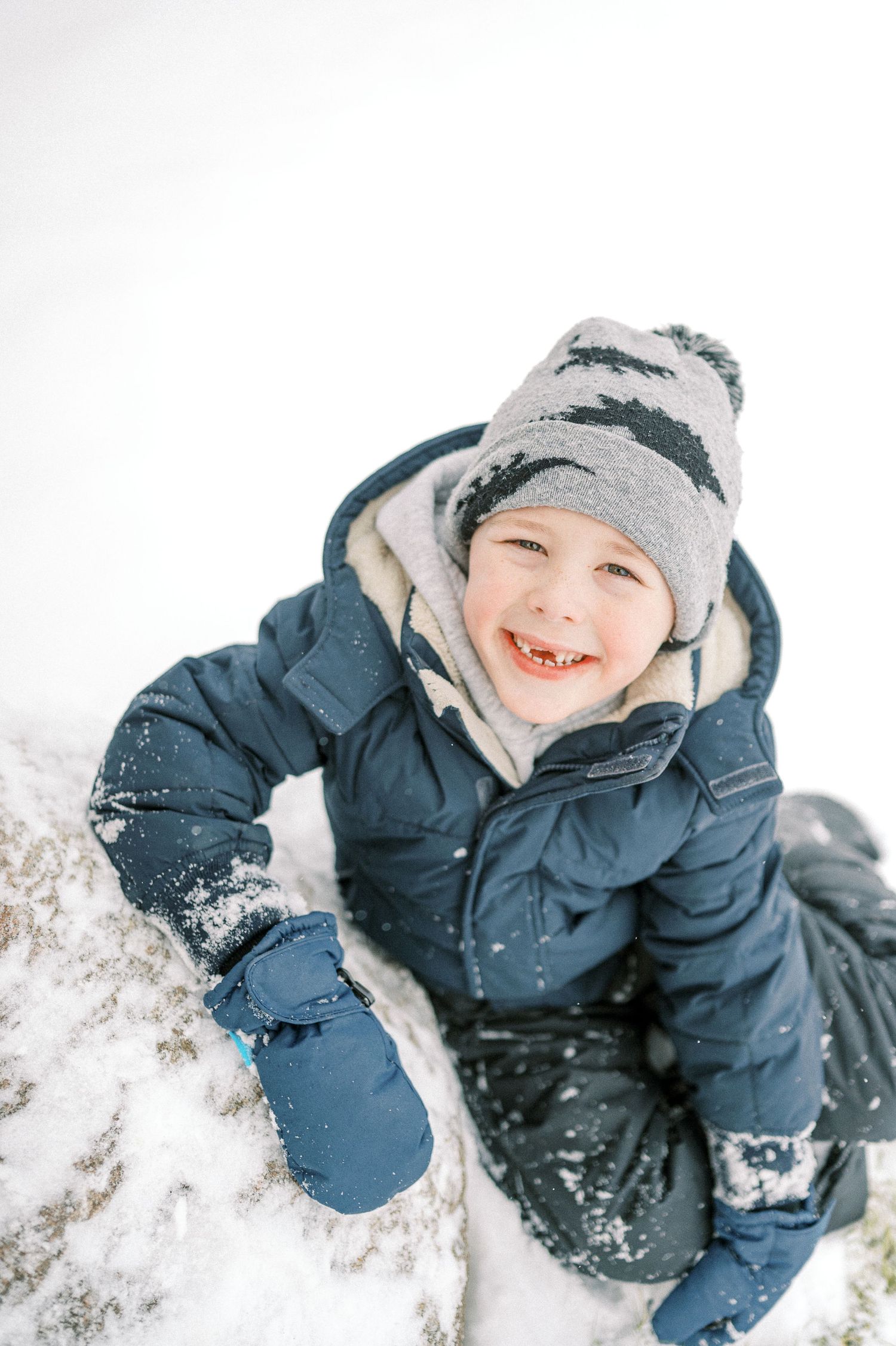 Close-up winter action shots of someone playing in the snow wearing a navy blue coat.