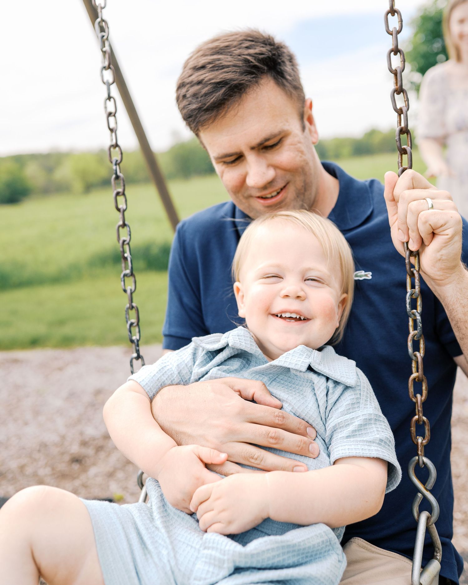 Parent and child share joyful moments together while playing on a swing in a park setting.