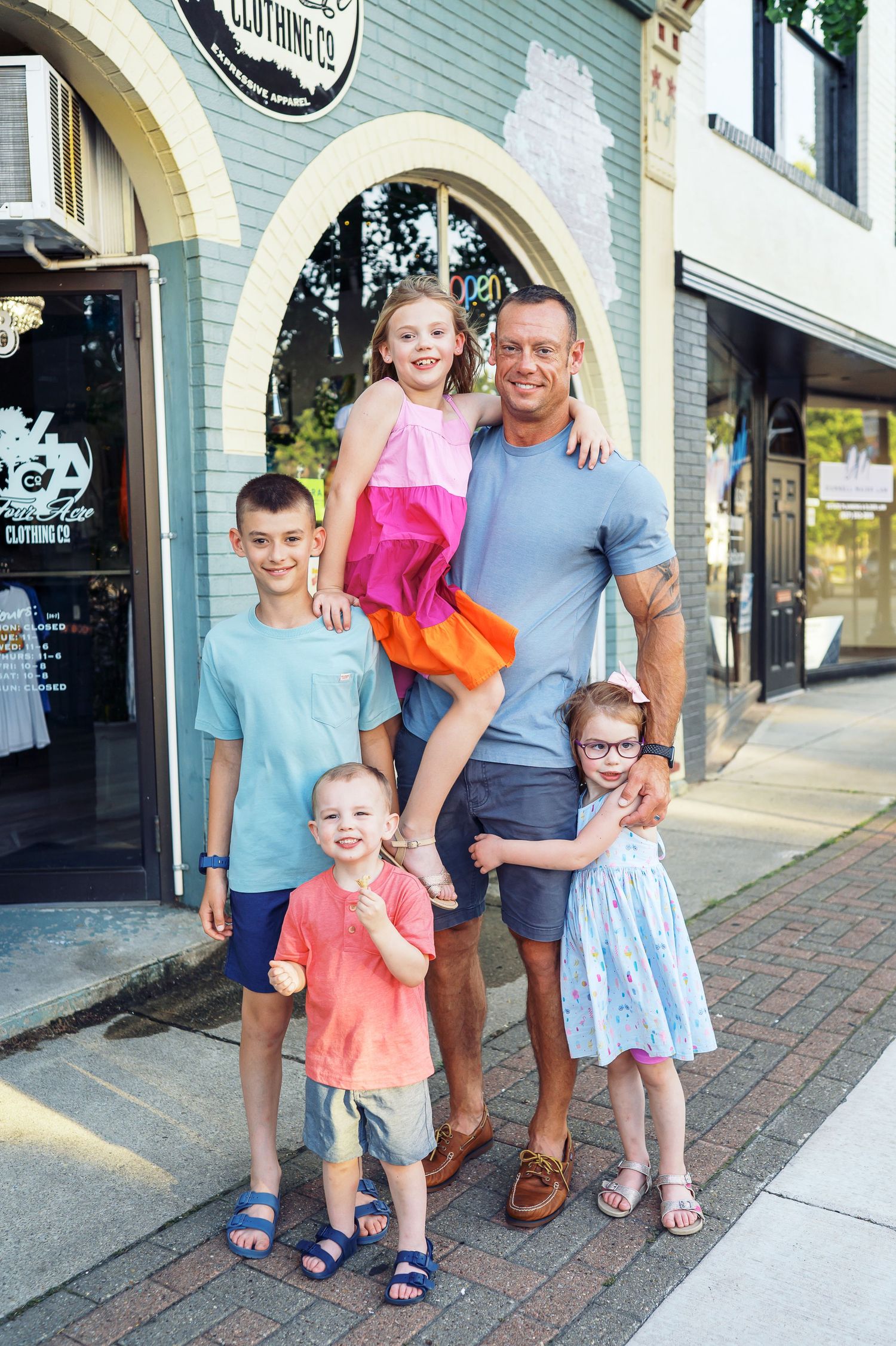 Group portrait outside storefront with arched doorway and brick sidewalk.