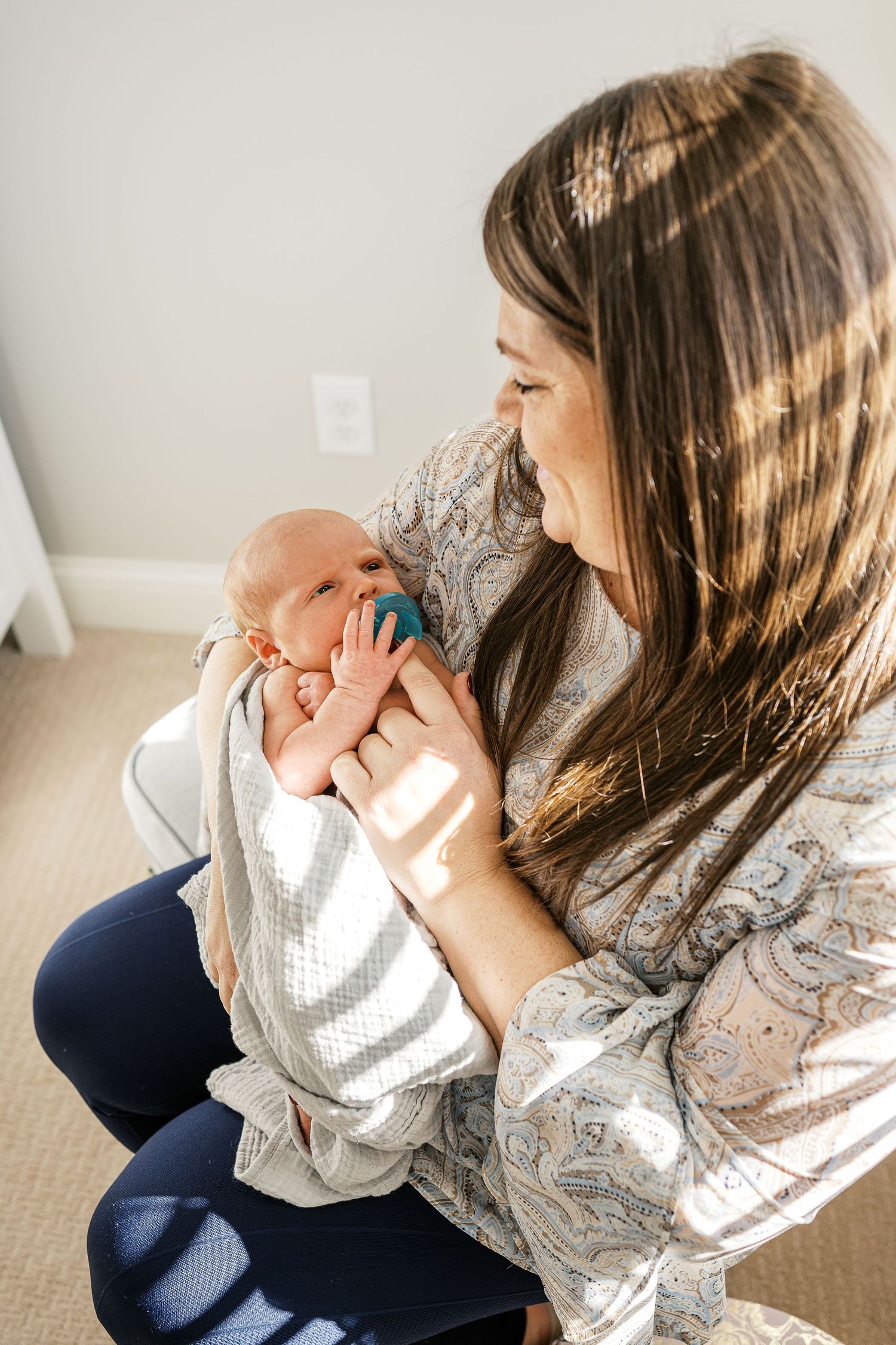 Parent cradling and kissing newborn baby in a peaceful home setting.