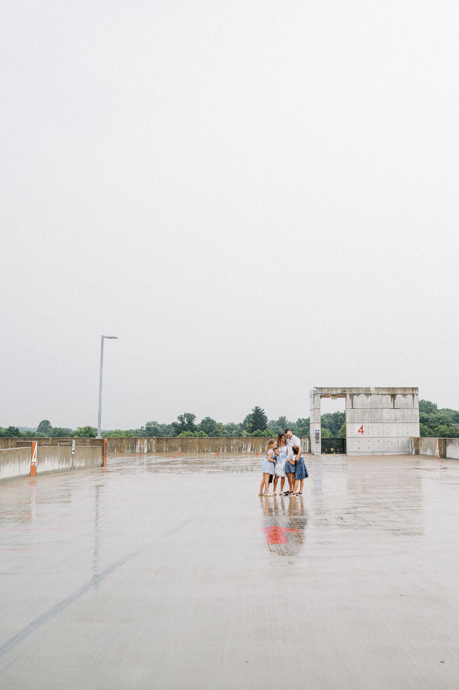 People enjoying a rainy day on a wet concrete surface with lamp posts in the background.