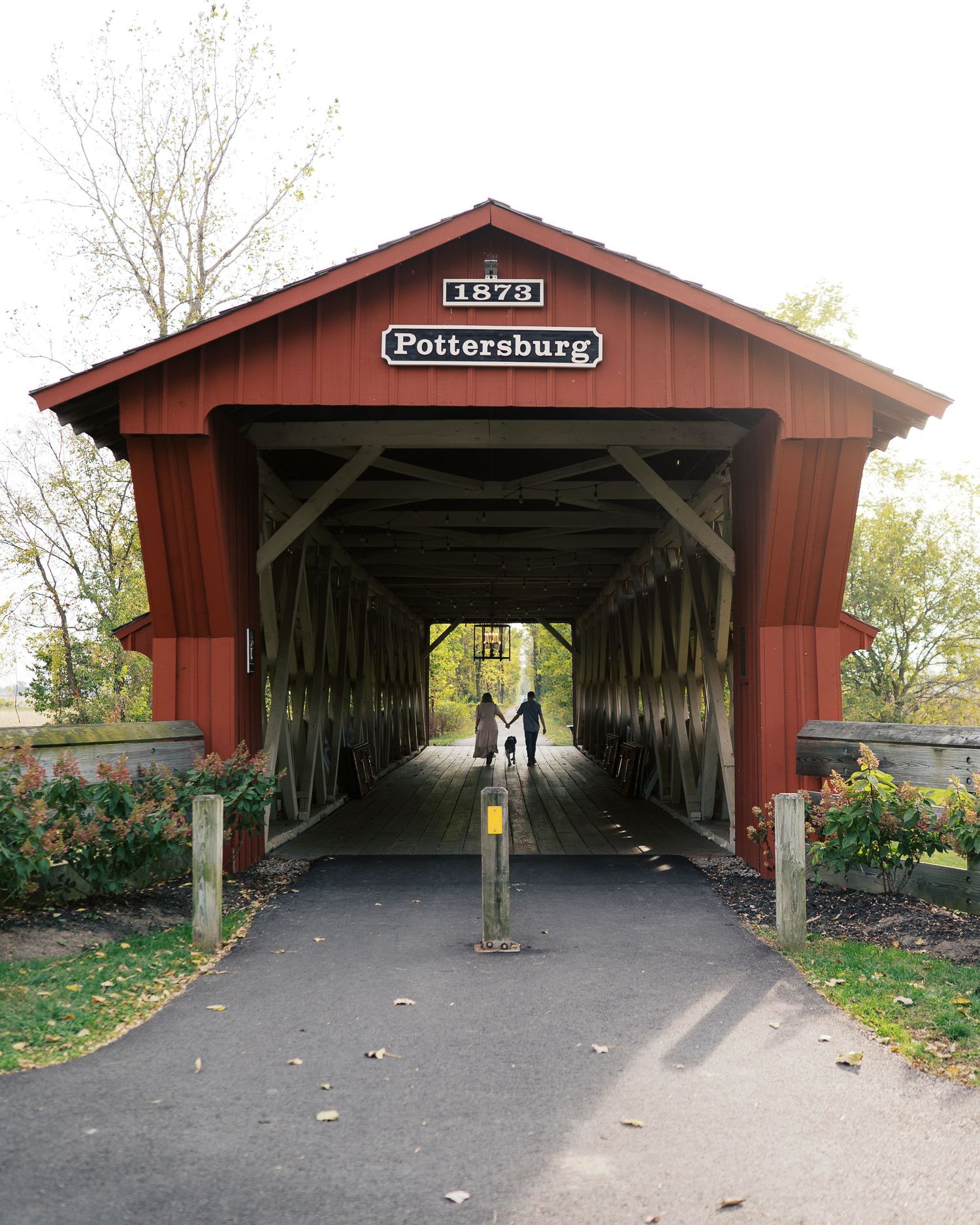 A series of five views showing the entrance and interior of a red covered bridge in autumn with fallen leaves on the ground.