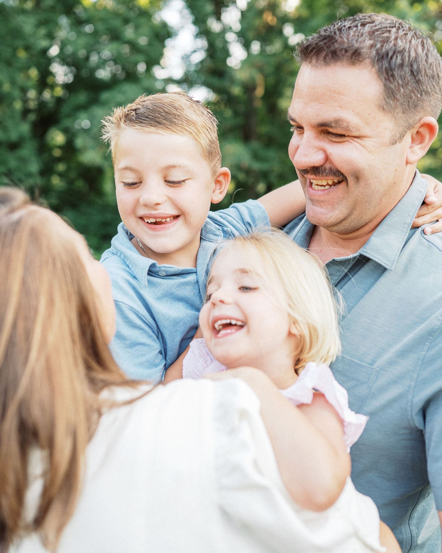 Joyful family moment with everyone laughing together outdoors.