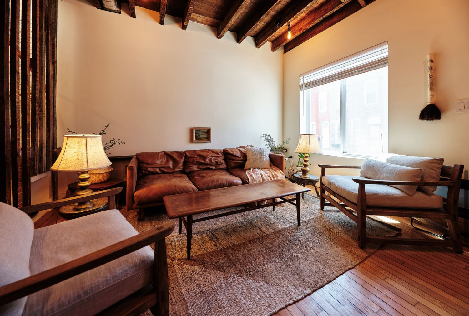 Mid-century modern living room with exposed joists and leather couch in Baltimore City. Architectural real estate photography.