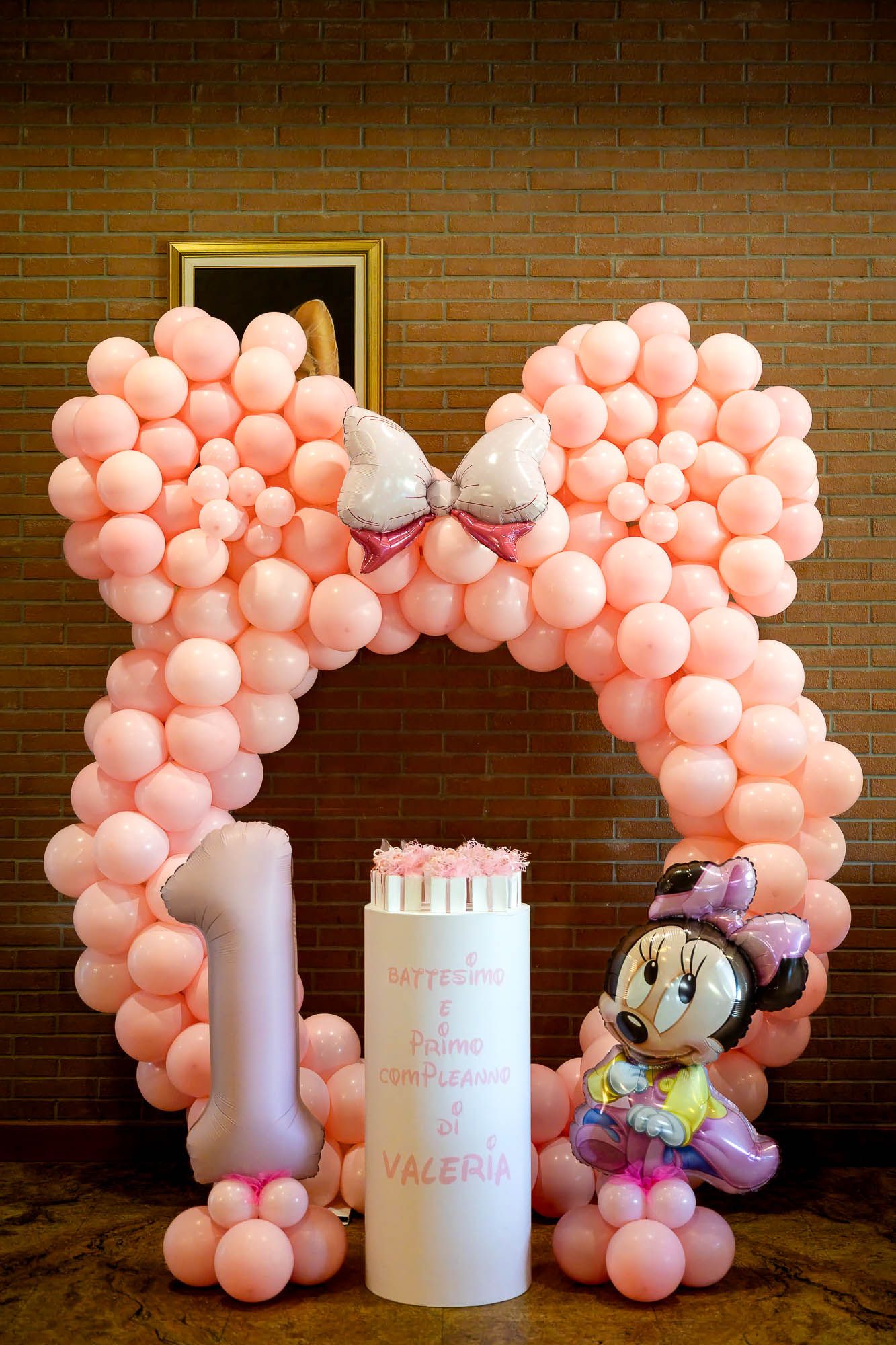 Pink balloon arch with Minnie Mouse decor and number 1 for Valeria's first birthday party celebration.