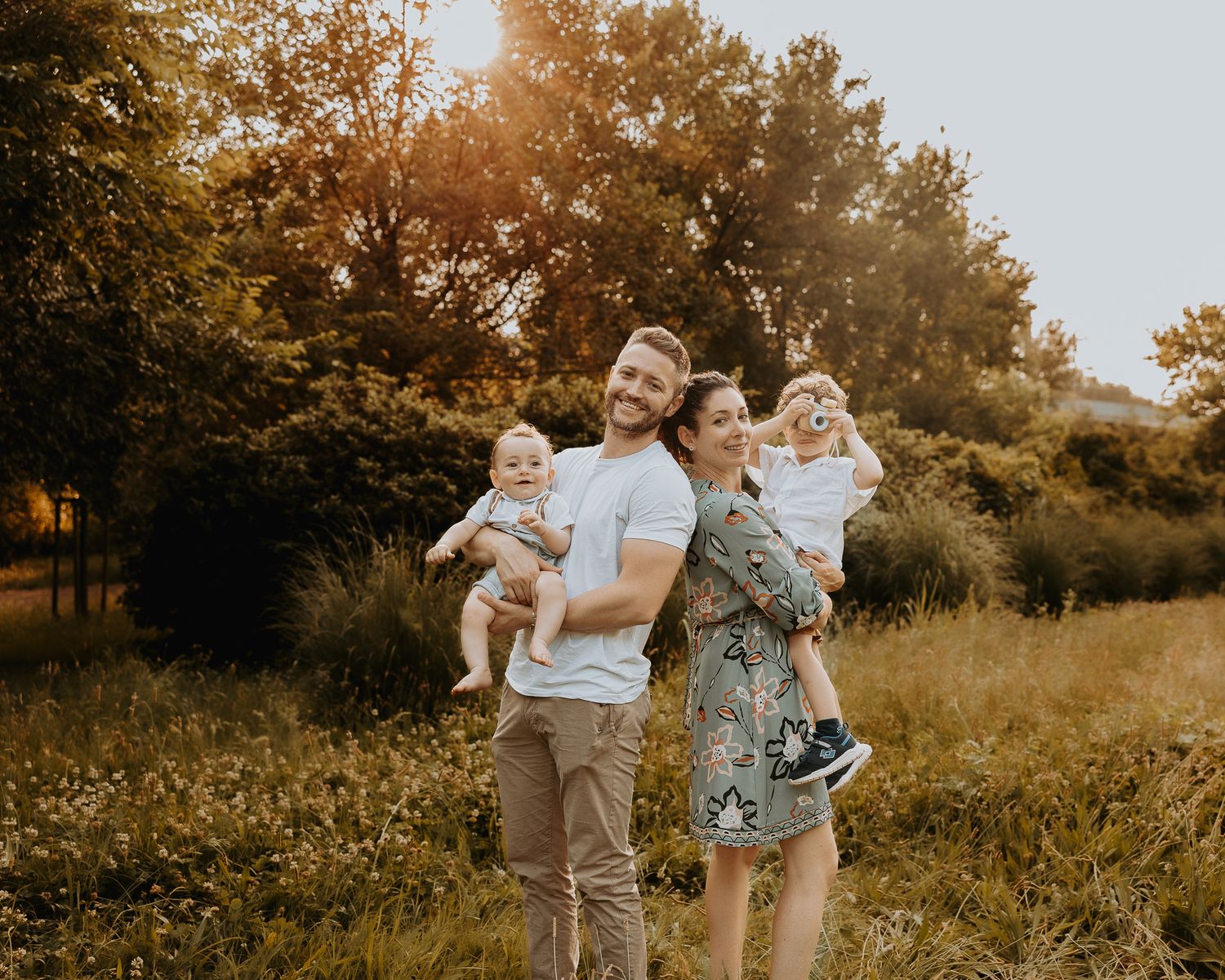 Family enjoying a sunset moment together in a golden field with wildflowers.