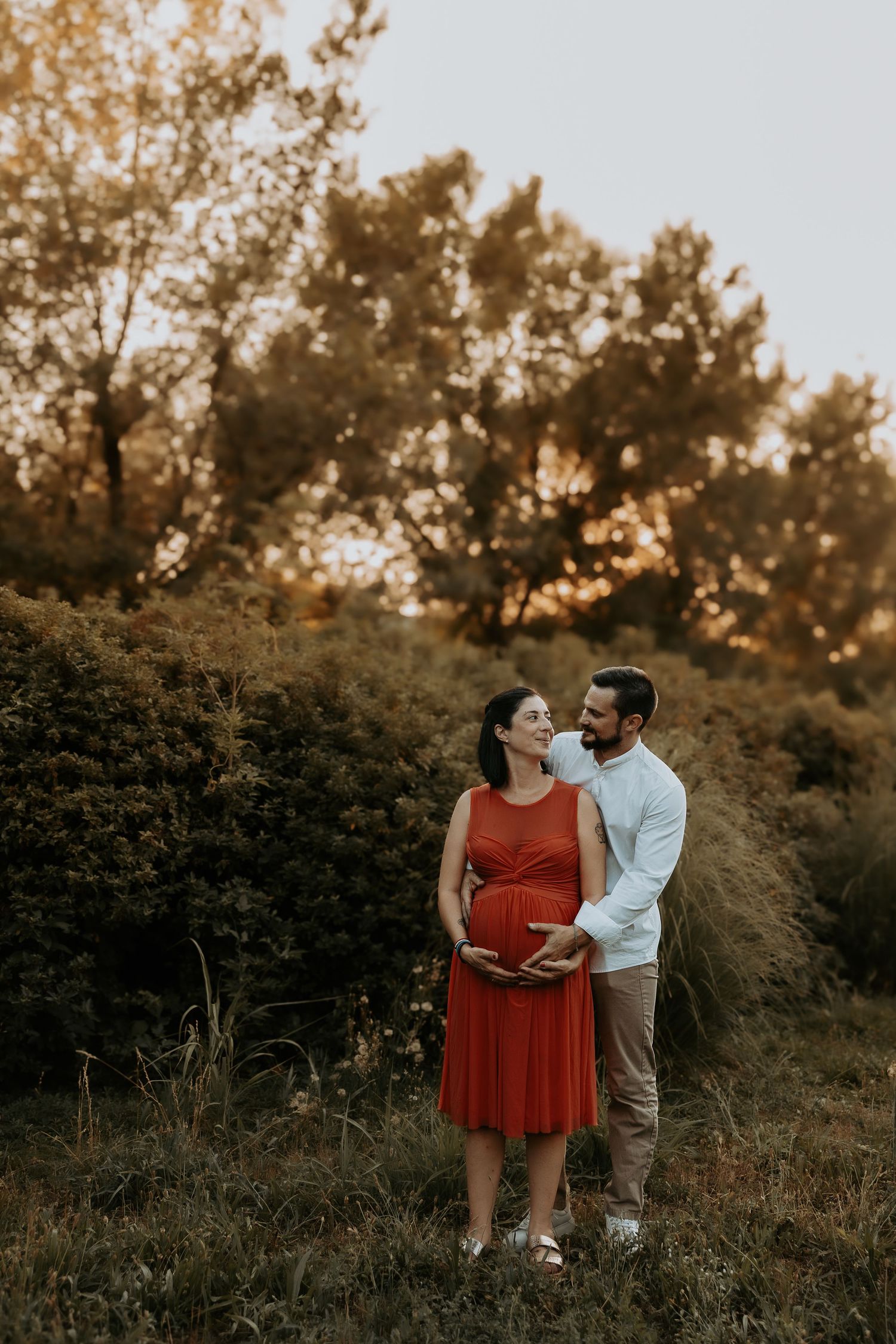 Sunset maternity photoshoot in nature with warm golden lighting.