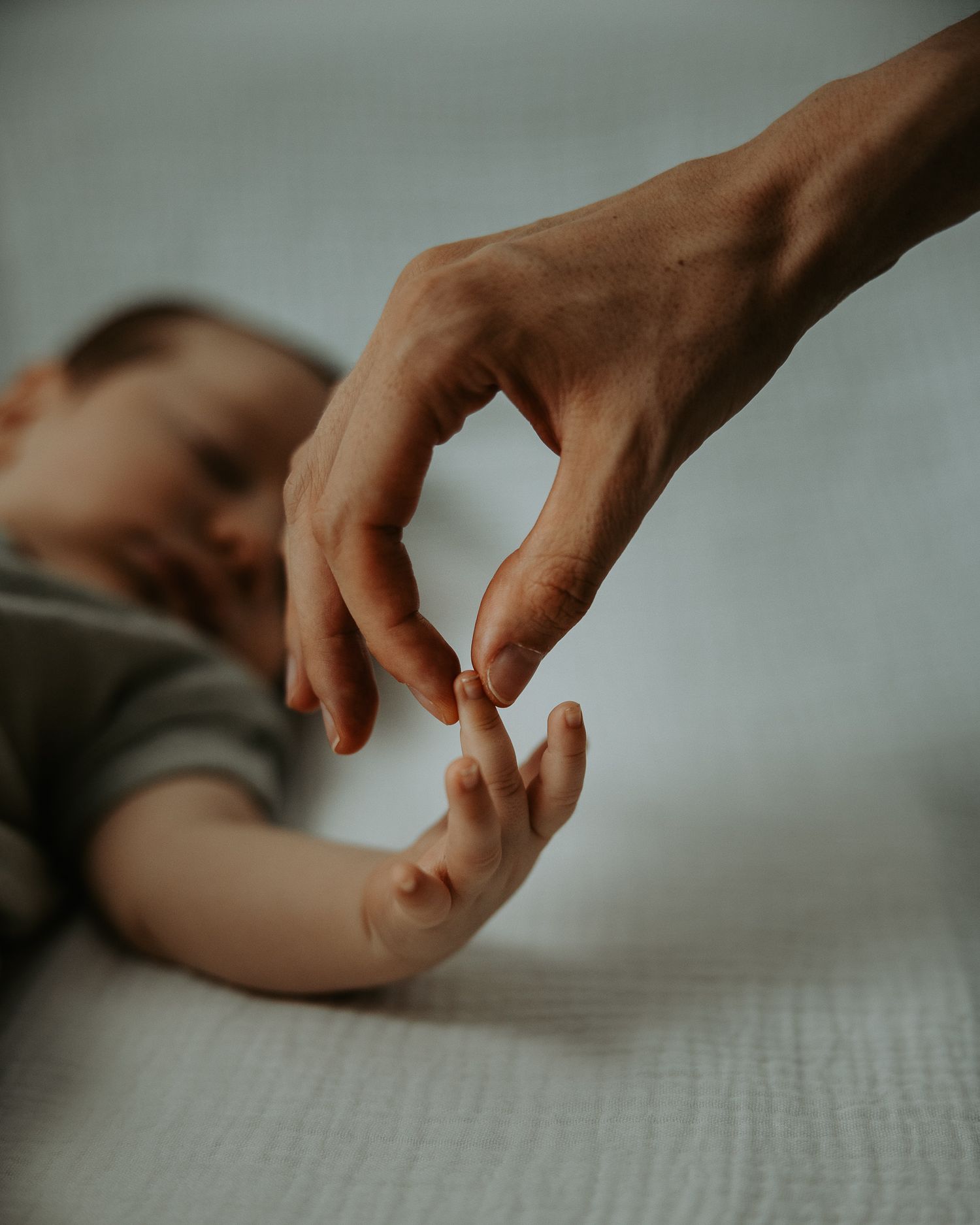 Close-up series of hands reaching and touching across a light surface.