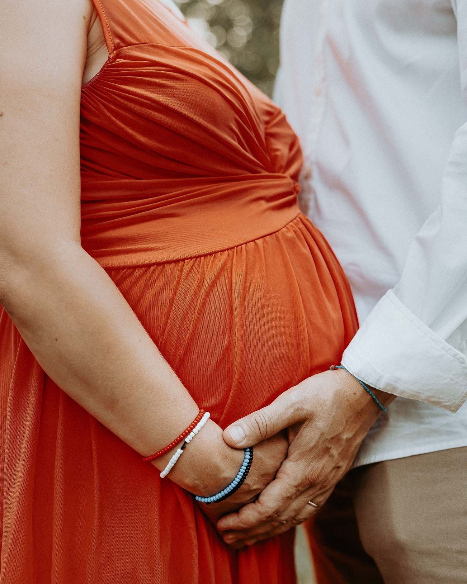 Dettaglio pancione gravidanza con mani dei genitori sulla pancia durante servizio maternity al parco Lambretta