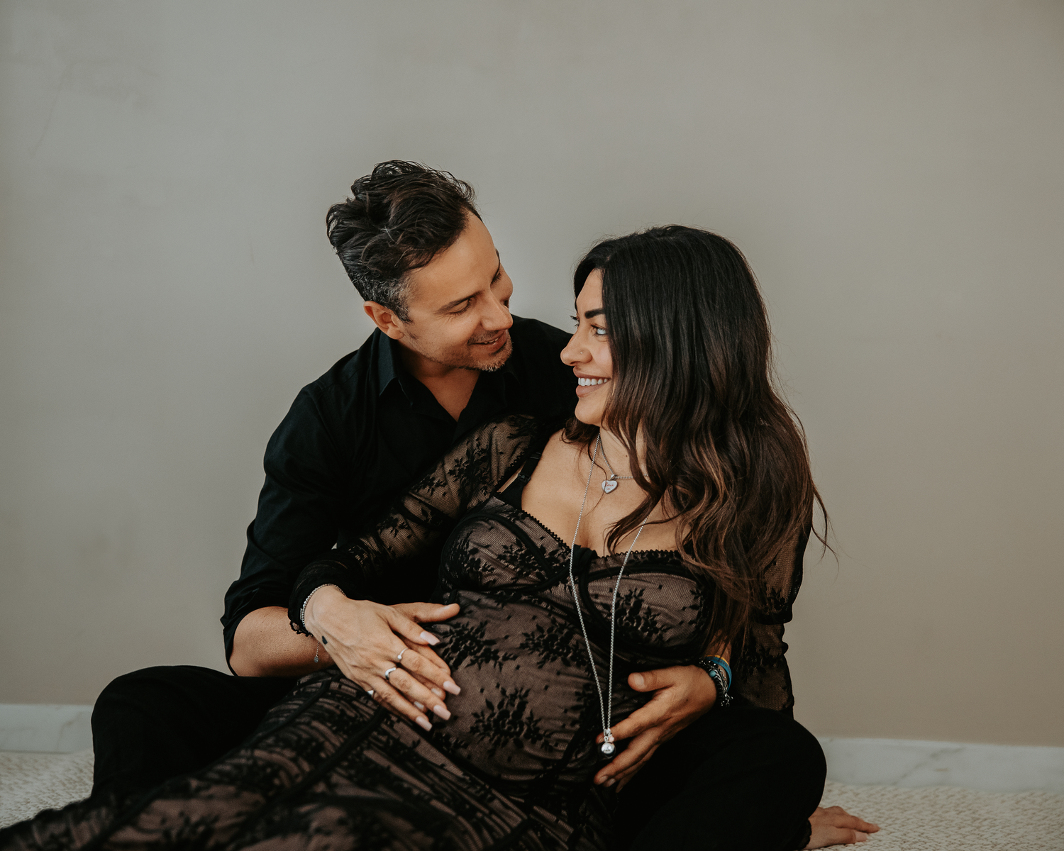 Intimate couple's boudoir photoshoot featuring romantic poses in black lace against a neutral background.