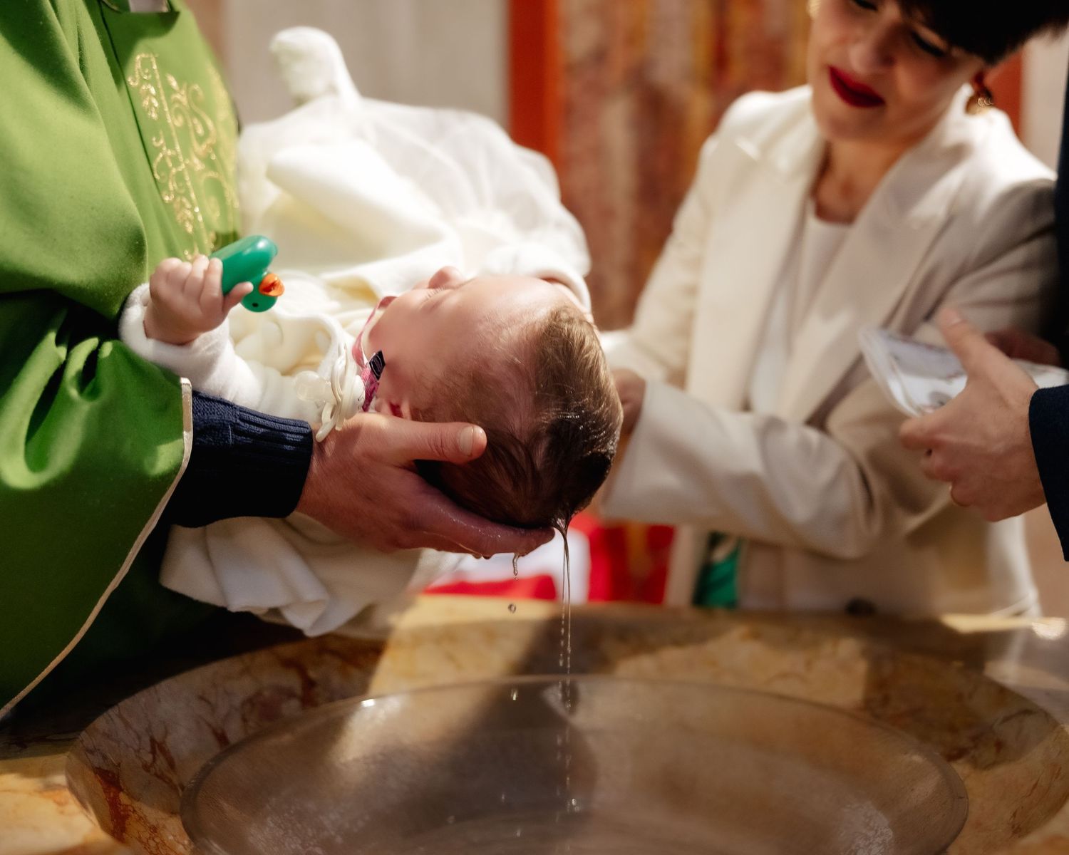 Religious baptism ceremony with priest performing traditional blessing.