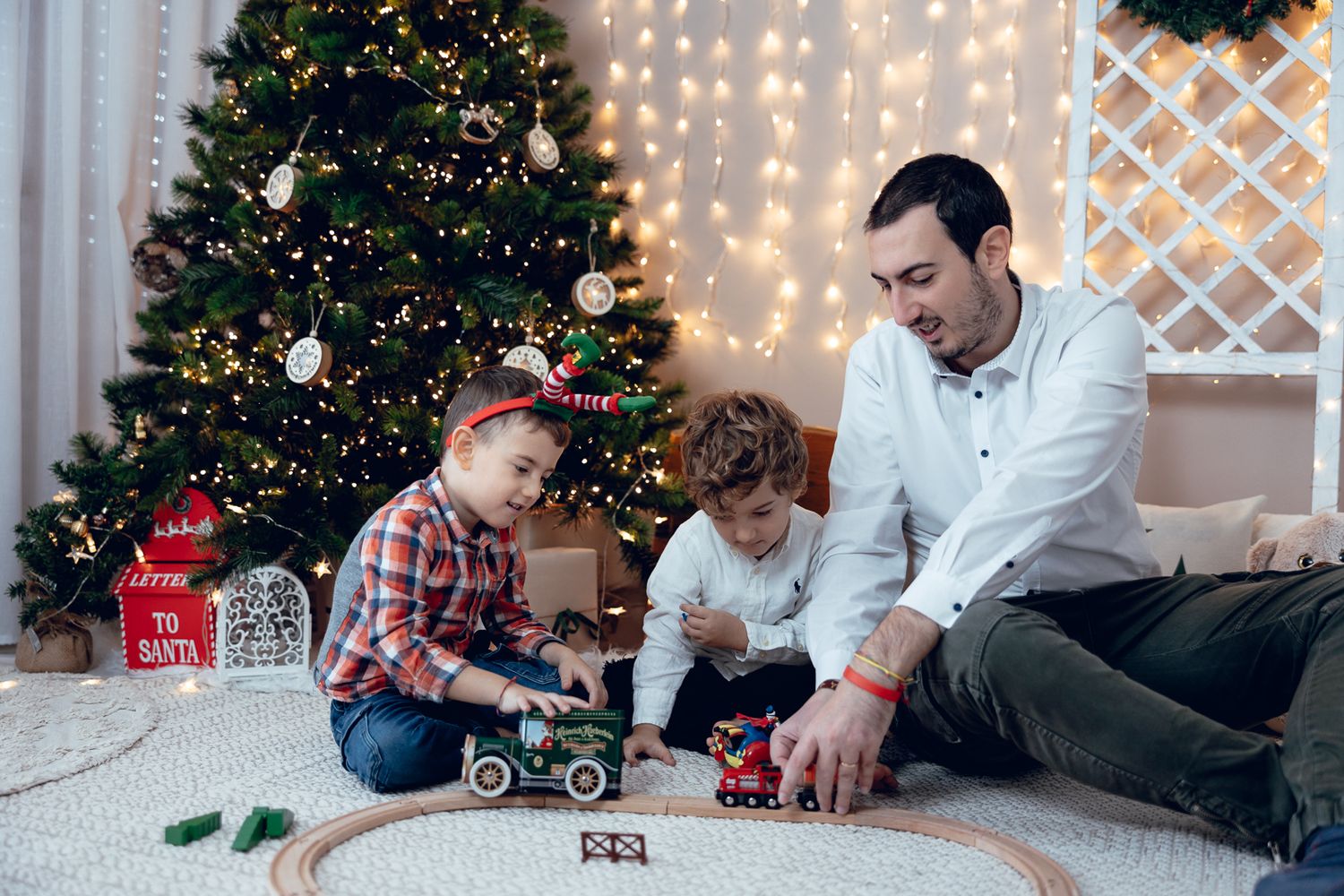 Candid family moments during Christmas photoshoot with decorated tree and lights.