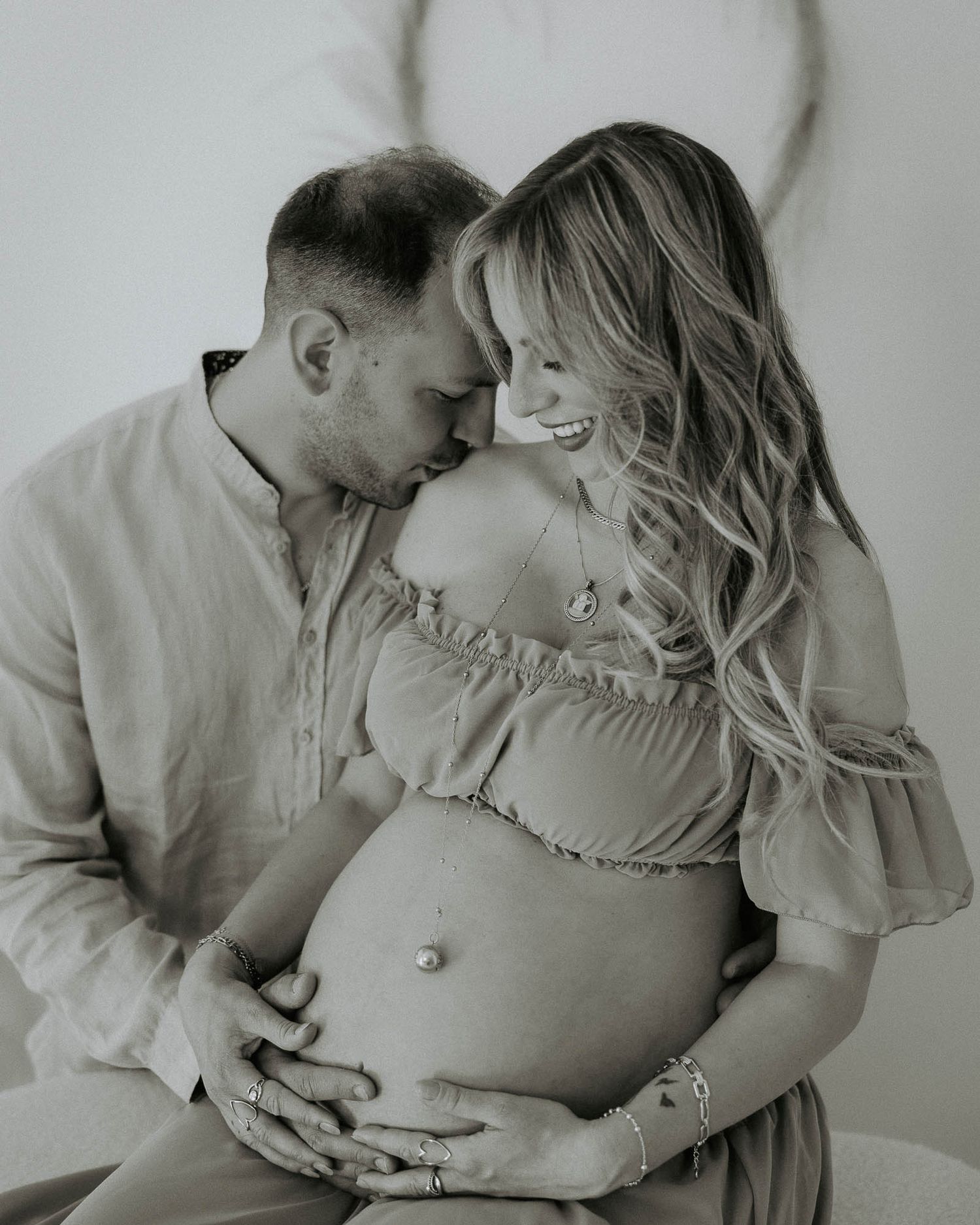 Foto di maternità in bianco e nero di una coppia che si abbraccia teneramente in studio a Milano