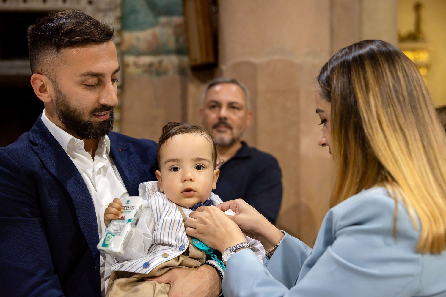 Parents dressing baby during baptism ceremony in a church.