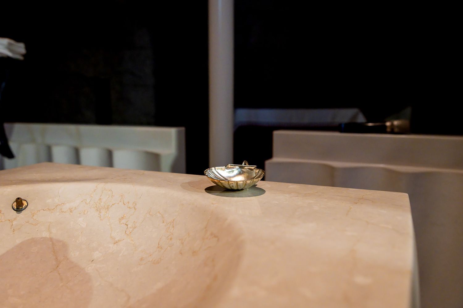Elegant marble sink countertop with a decorative gold shell dish accent in a luxury bathroom setting.