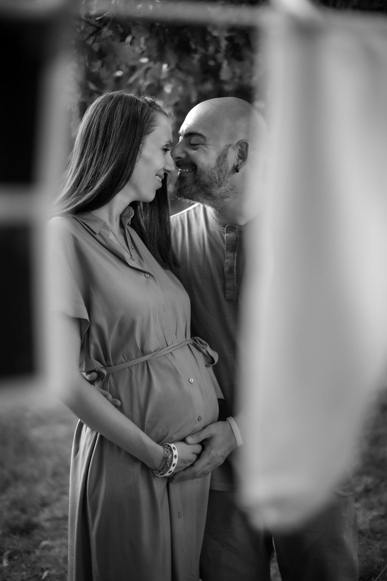 Romantic black and white maternity photoshoot with couple embracing.