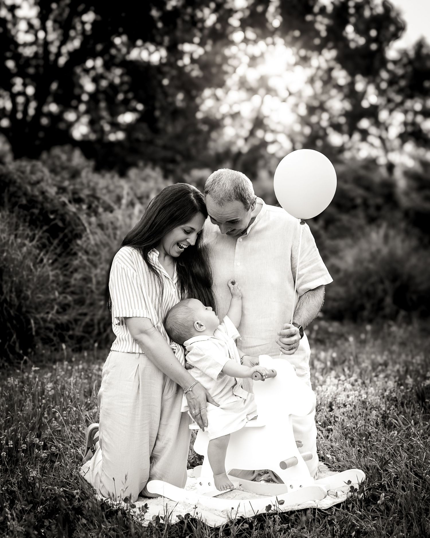 Famiglia con bambino durante un servizio fotografico per il primo compleanno all’aperto con palloncini