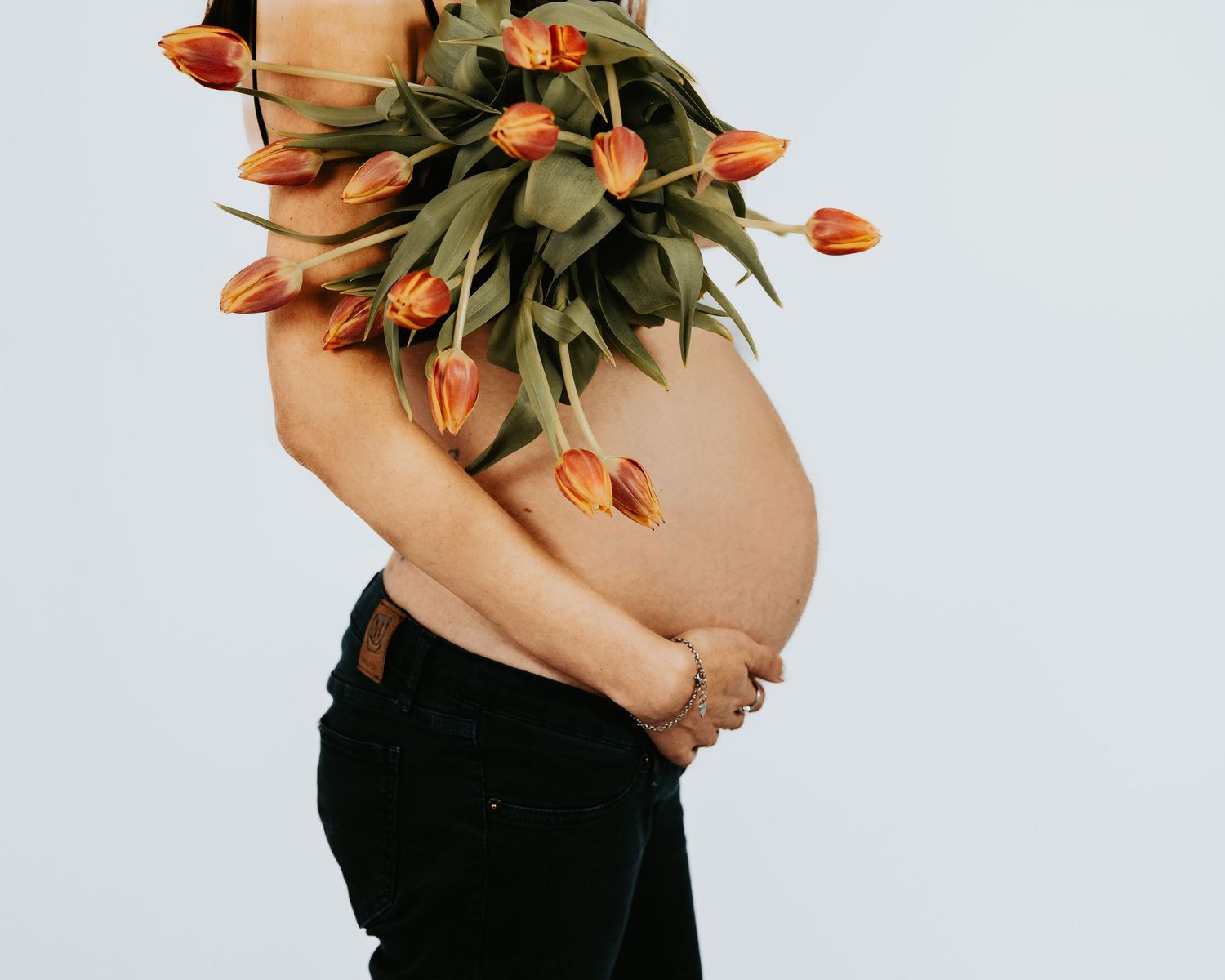 Fotografia artistica di gravidanza con pancione e tulipani. Fotografa maternità a Milano, stile autentico.