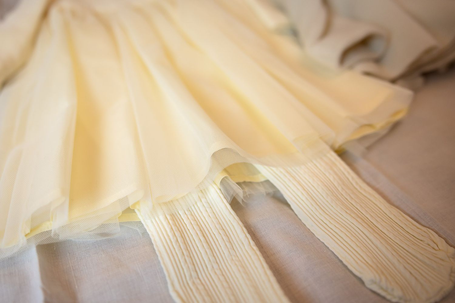 Close-up of delicate pleated cream chiffon fabric layers of an elegant wedding dress laid flat.