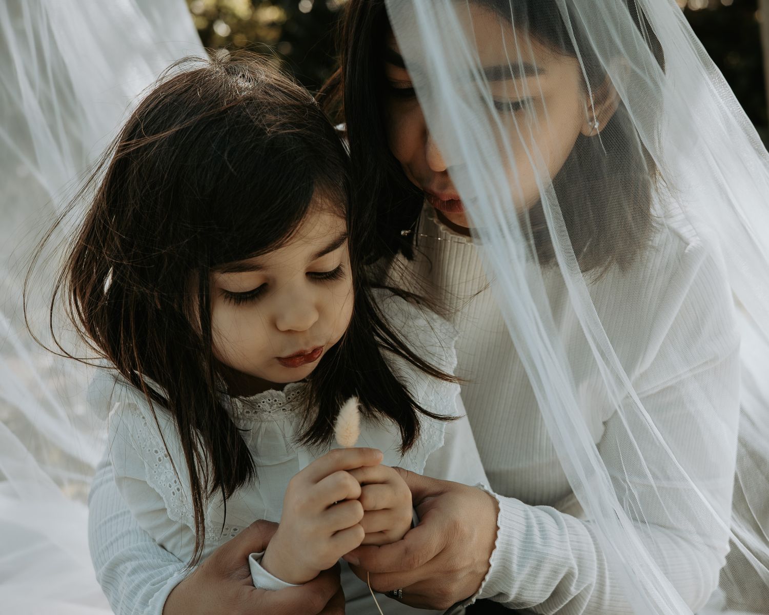 Intimate moments captured between parent and child under flowing white veil.