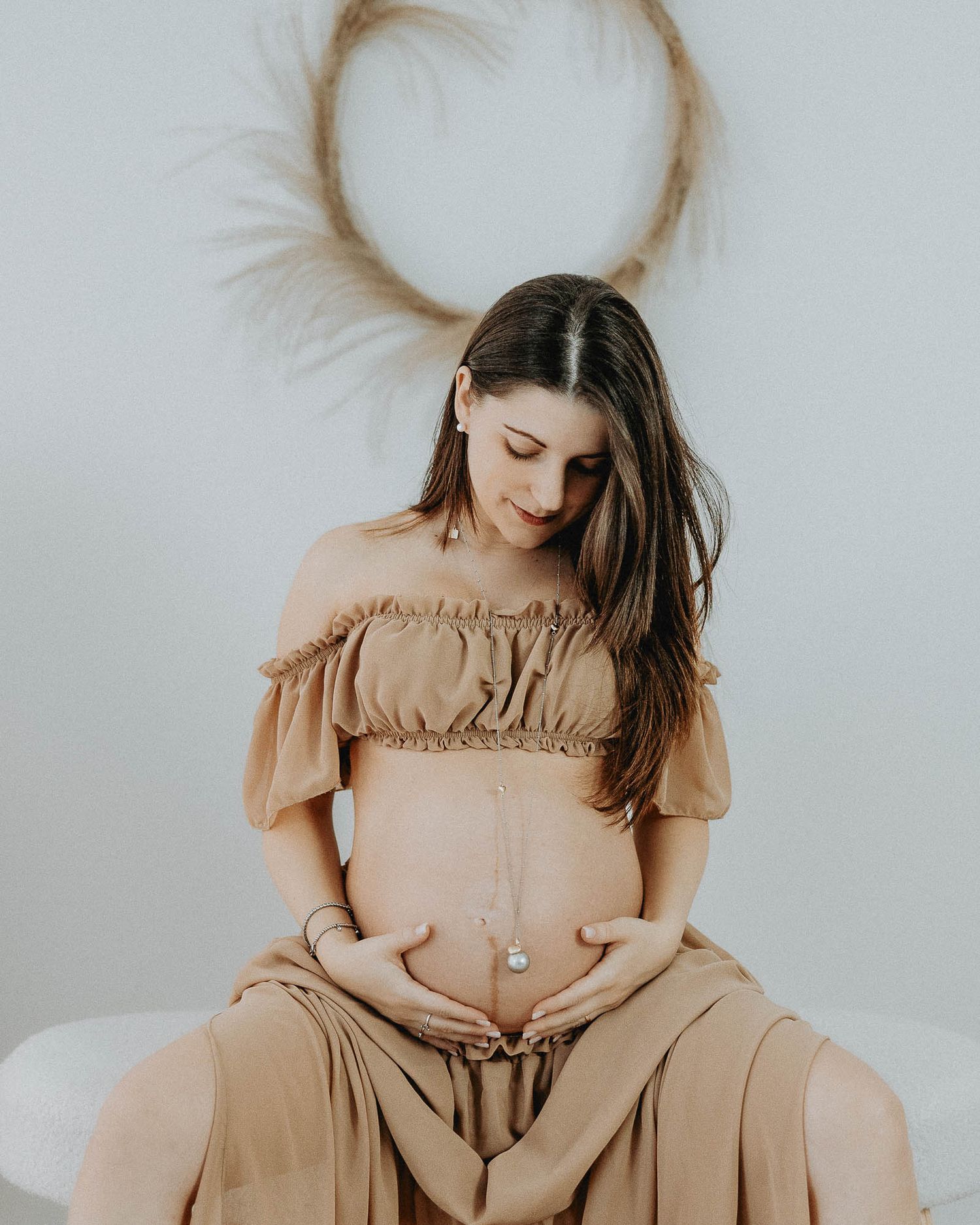 Donna incinta seduta in studio fotografico maternity minimal a Milano zona Città Studi