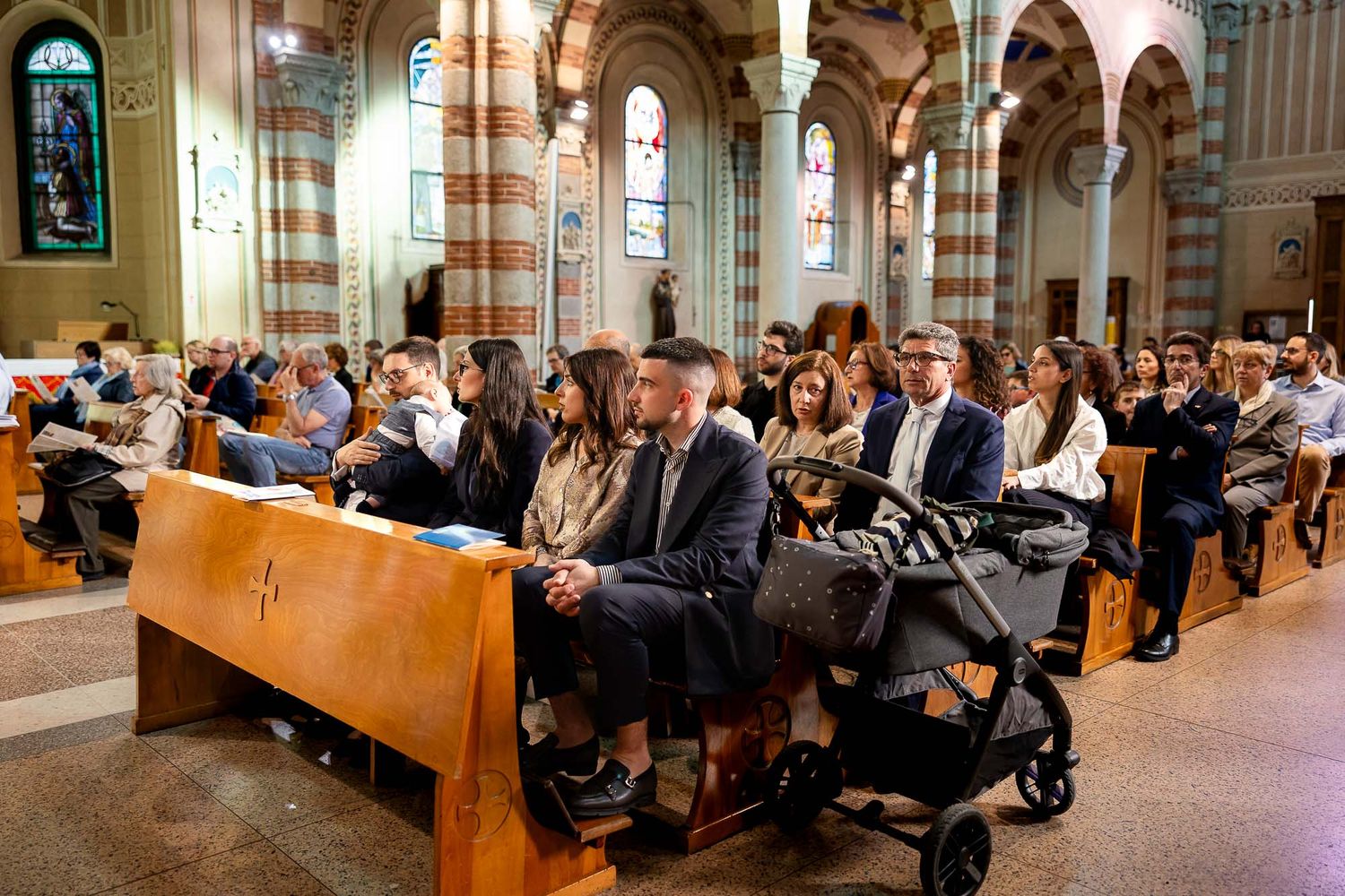 Congregation seated in ornate church pews during a Catholic baptism ceremony.