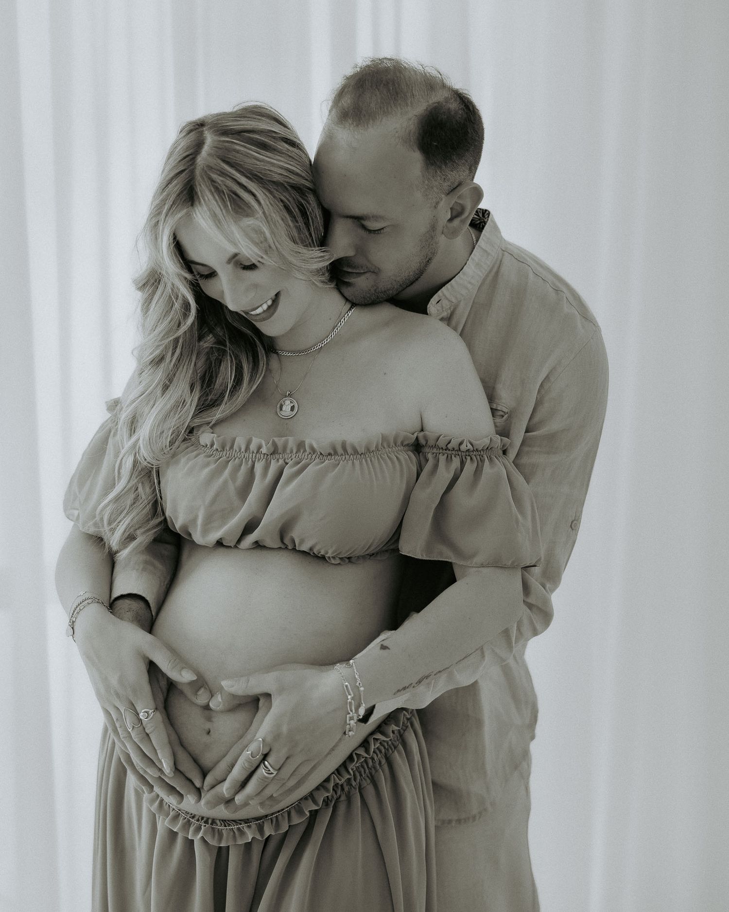 Foto di maternità in bianco e nero di una coppia che si abbracciano in un studio fotografico a Milano zona Rubattino