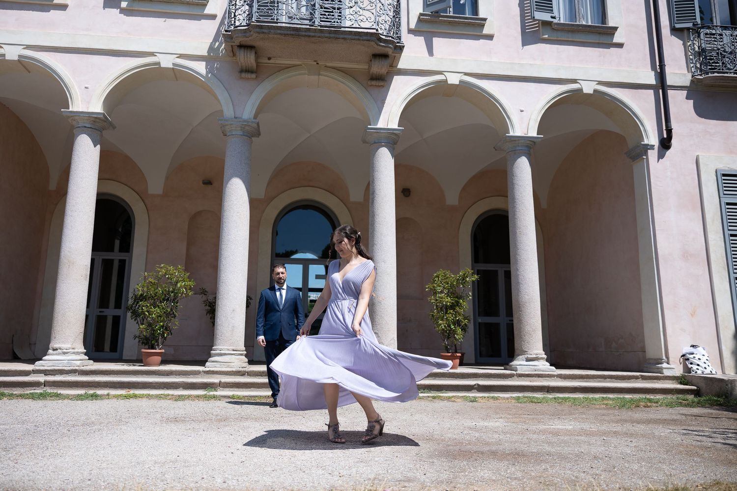 A panoramic view of a white building exterior with arched colonnade walkways and decorative architectural details.
