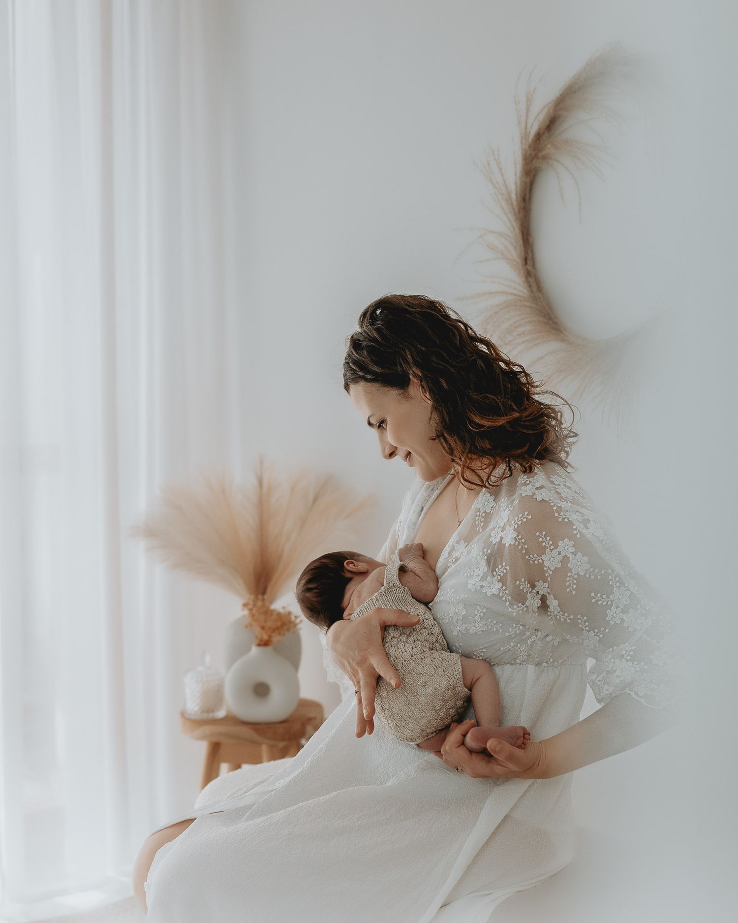 Mamma culla il suo bambino seduta vicino alla finestra.