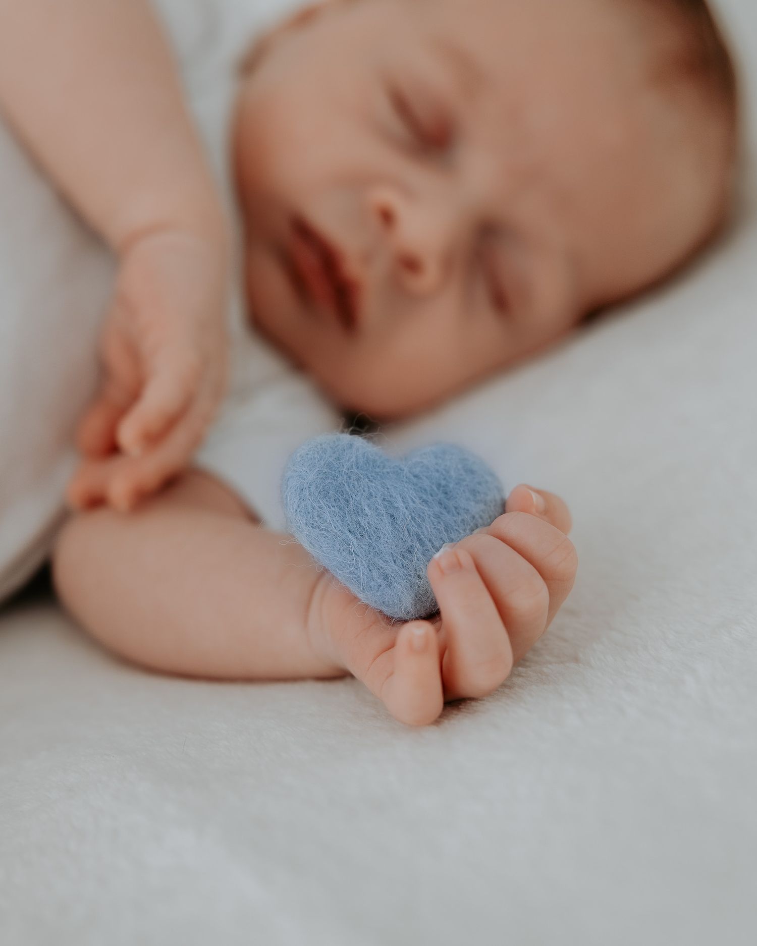 Dettaglio della manina del neonato con cuore azzurro.