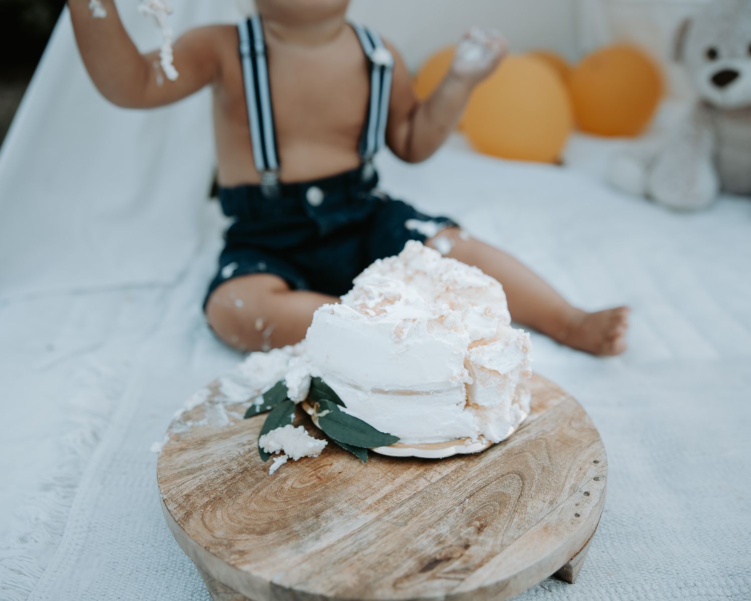 Close-up of white cake on rustic wooden platter with floral decorations.