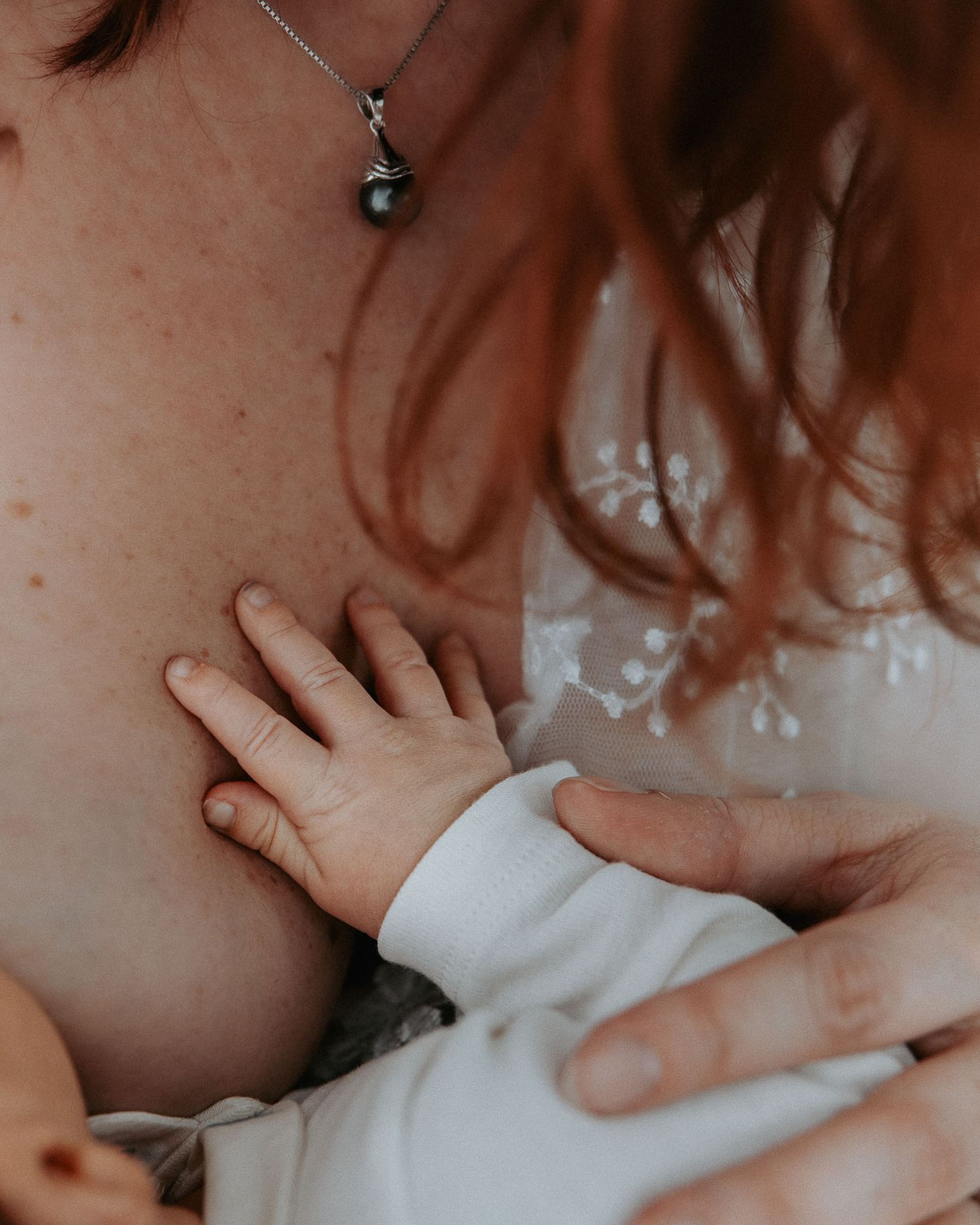 Dettaglio della mano del neonato appoggiata sul petto della mamma.