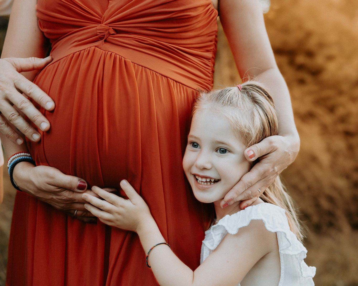 Dettaglio maternity con bambina che abbraccia il pancione della mamma